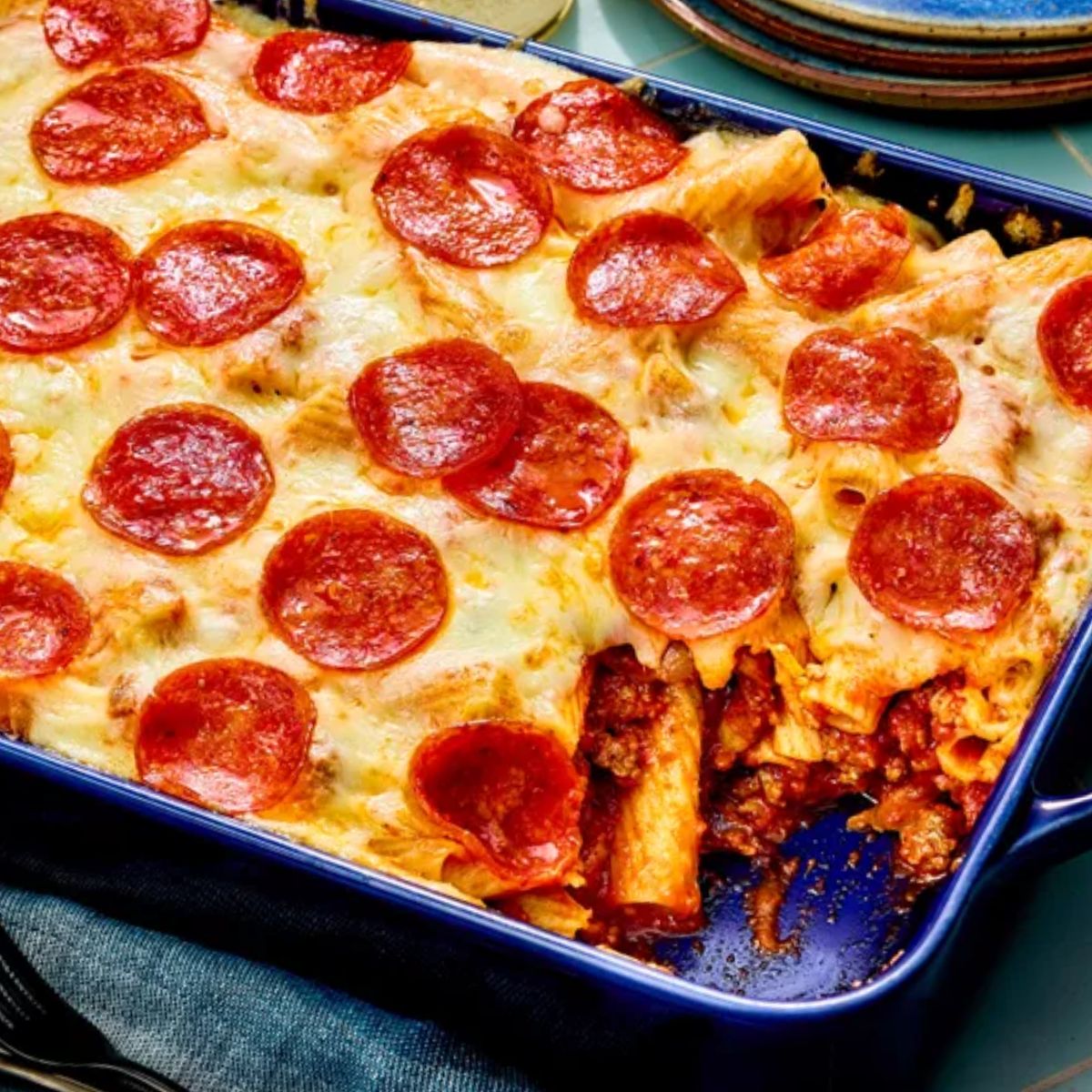 A baked manicotti casserole with melted cheese and crispy pepperoni on top. The dish is filled with pasta, rich meat sauce, and gooey mozzarella.
