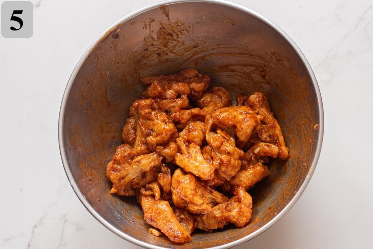 Toss the hot cauliflower with the sauce until coated, then finish with sesame seeds and green onions.