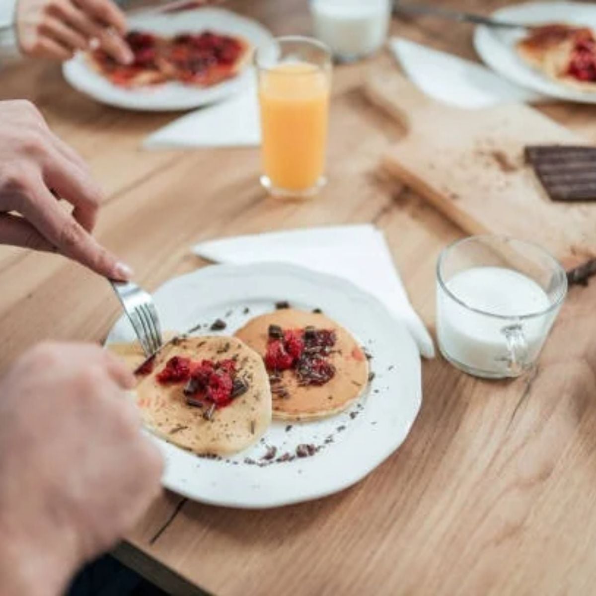 Pancakes With Chocolate Chips and chocolate shavings on the side of the plate, alongside a glass of milk
