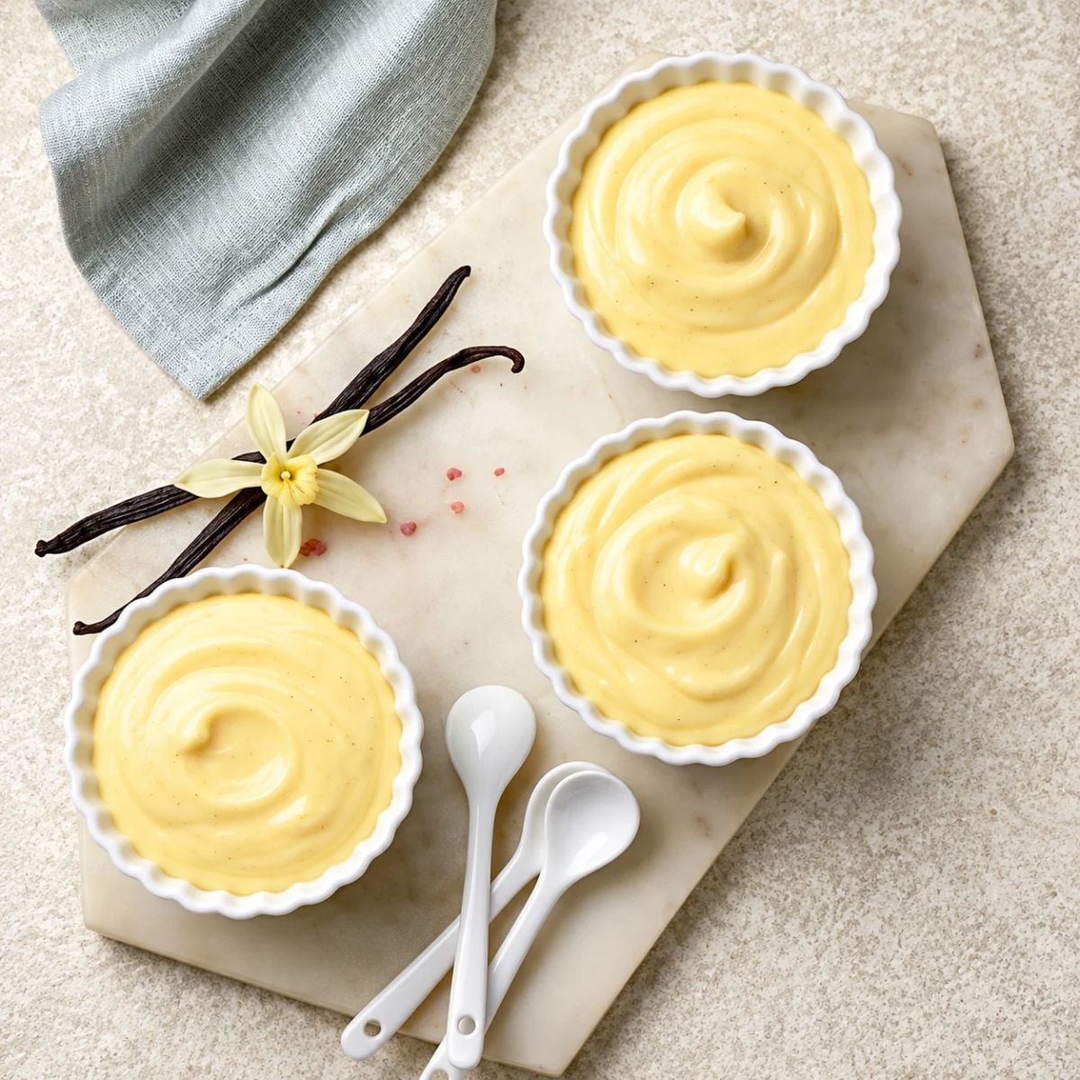 Vanilla Custard in Little Cups with 2 vanilla beans alongside it on a counter