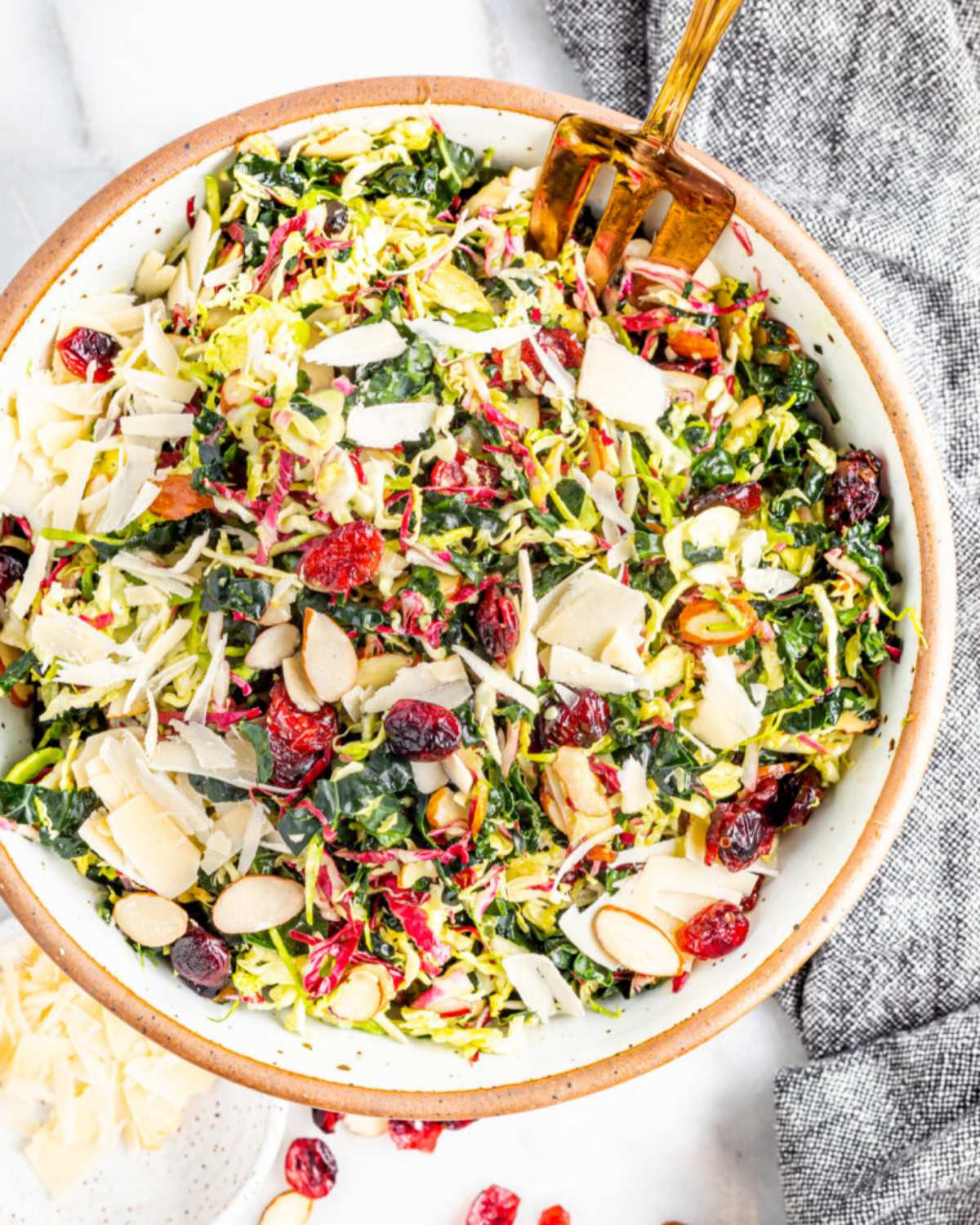 Winter coleslaw salad tossed with shaved cheese, cranberries, and almonds in a bowl, served as a cold Thanksgiving side dish