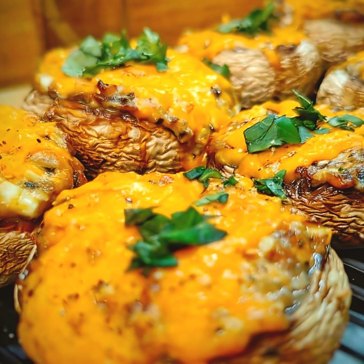 Air fryer stuffed mushrooms topped with melted cheese and fresh green herbs as an appetizer.