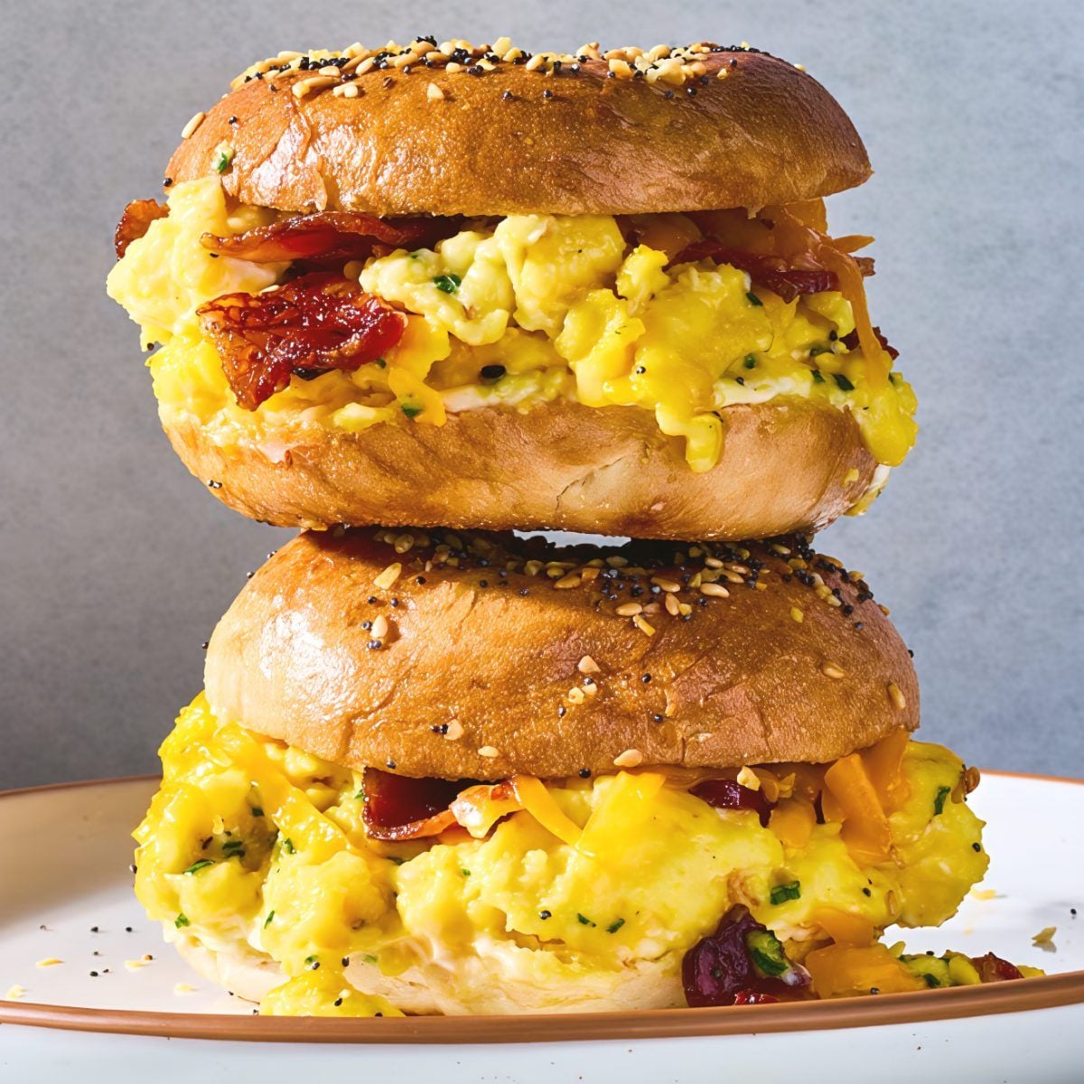 A vertical stack of loaded bagel breakfast sliders with eggs, bacon, and cheese, making an easy and crowd-pleasing brunch potluck idea for work.
