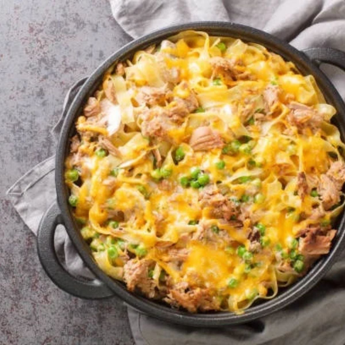 chicken and noodles in a pot with melted cheddar cheese on top