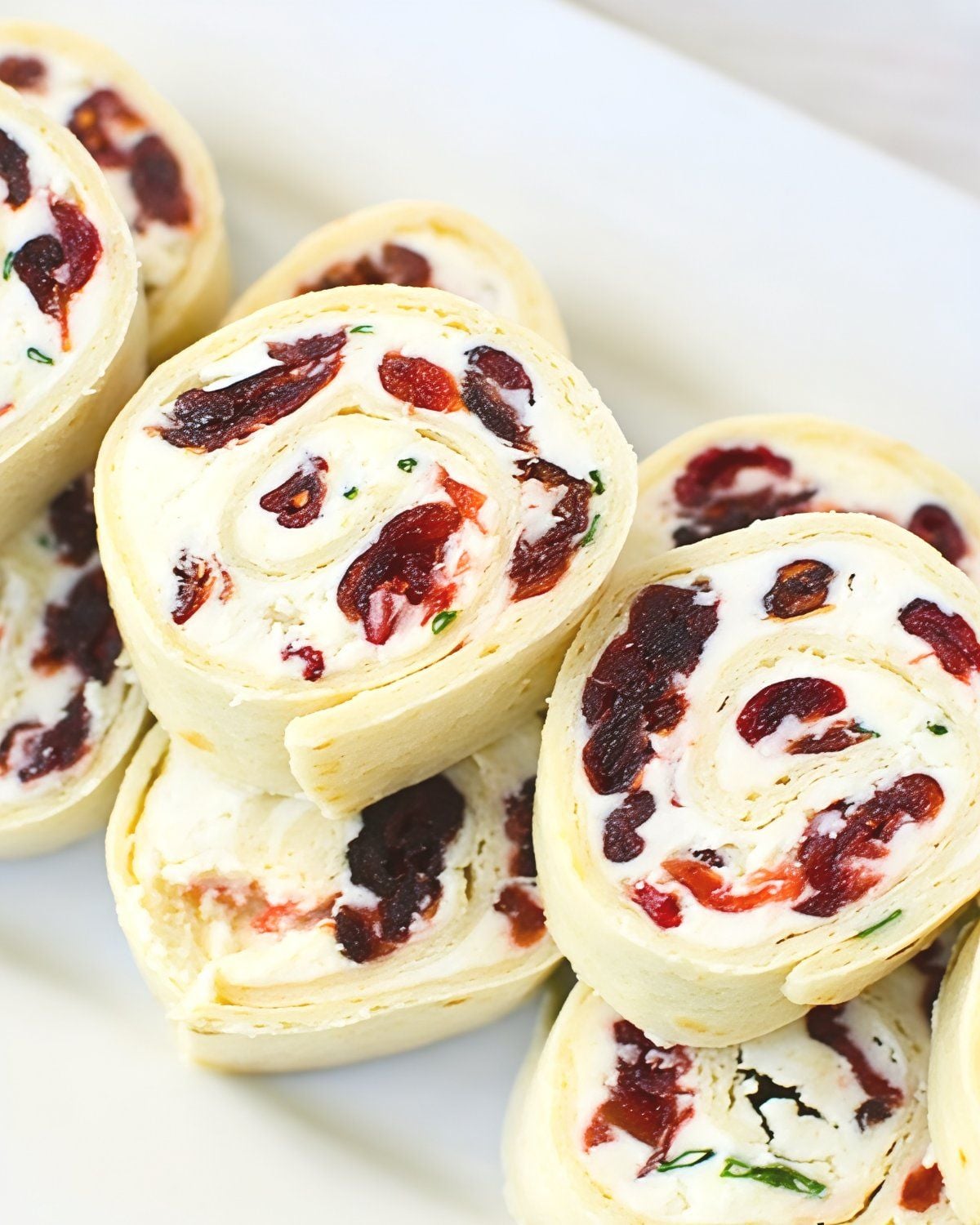 A platter of cranberry pinwheels served as a Thanksgiving appetizer, highlighting creamy filling and dried cranberries rolled in tortillas