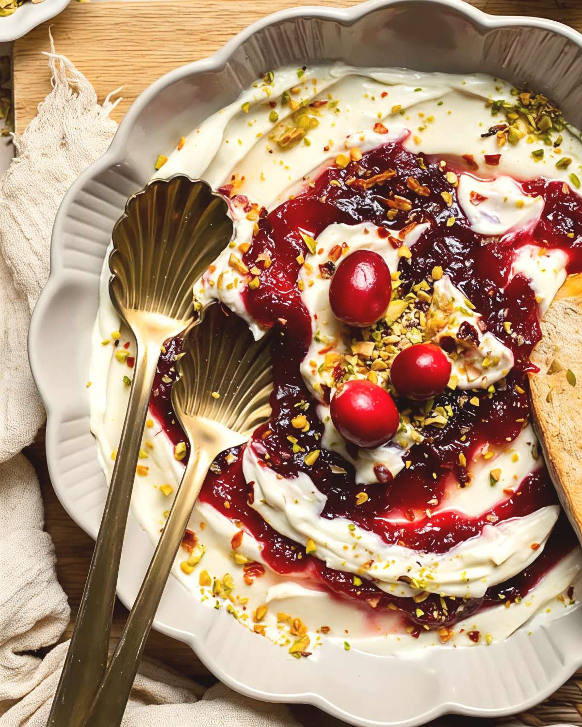 Cranberry whipped feta fall dip in a scalloped bowl, topped with whole cranberries and pistachios.