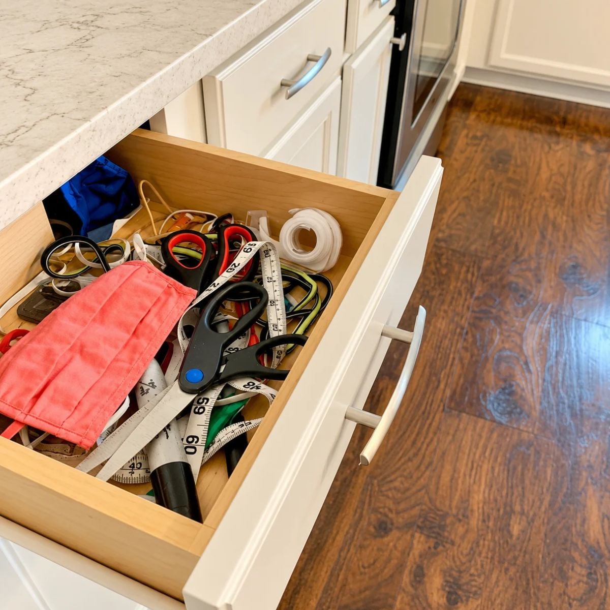 An open kitchen drawer holds twist ties and utensils.