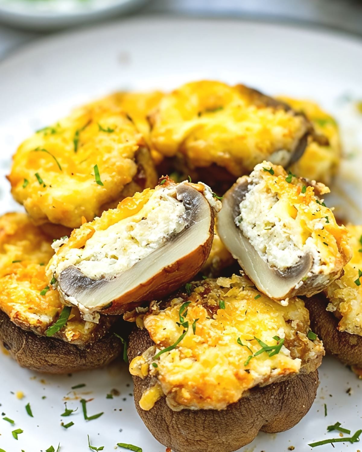A plate of mushrooms stuffed with cheese for a Thanksgiving appetizer, highlighting a cut piece revealing creamy filling