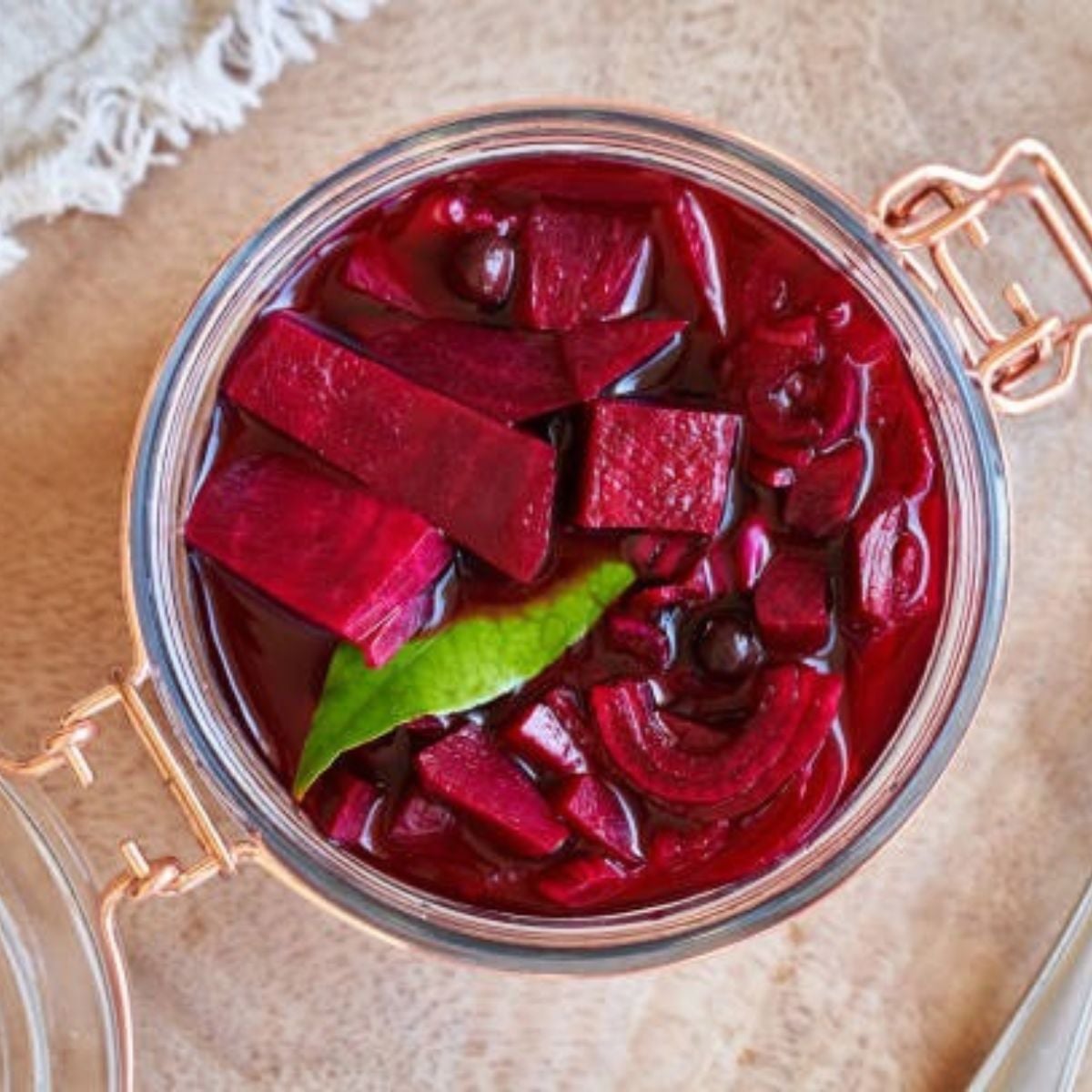 pickled beets in a glass jar on a light brown counter