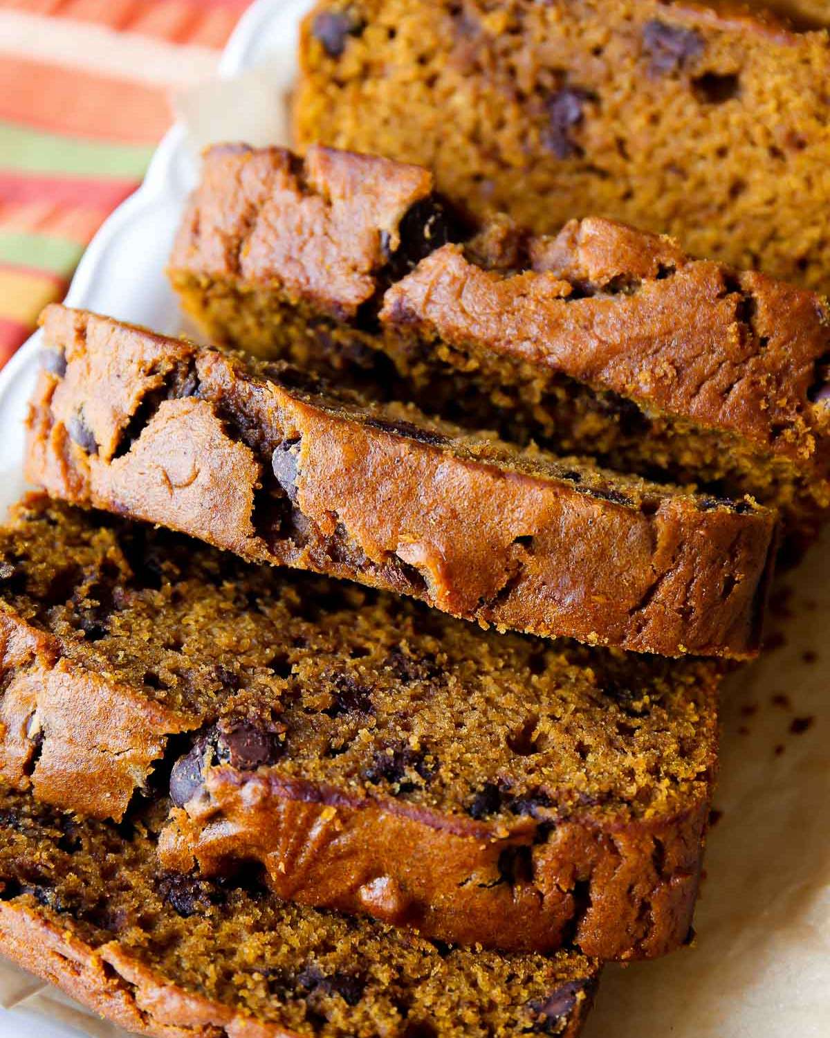 Slices of moist pumpkin chocolate chip bread stacked on a serving platter