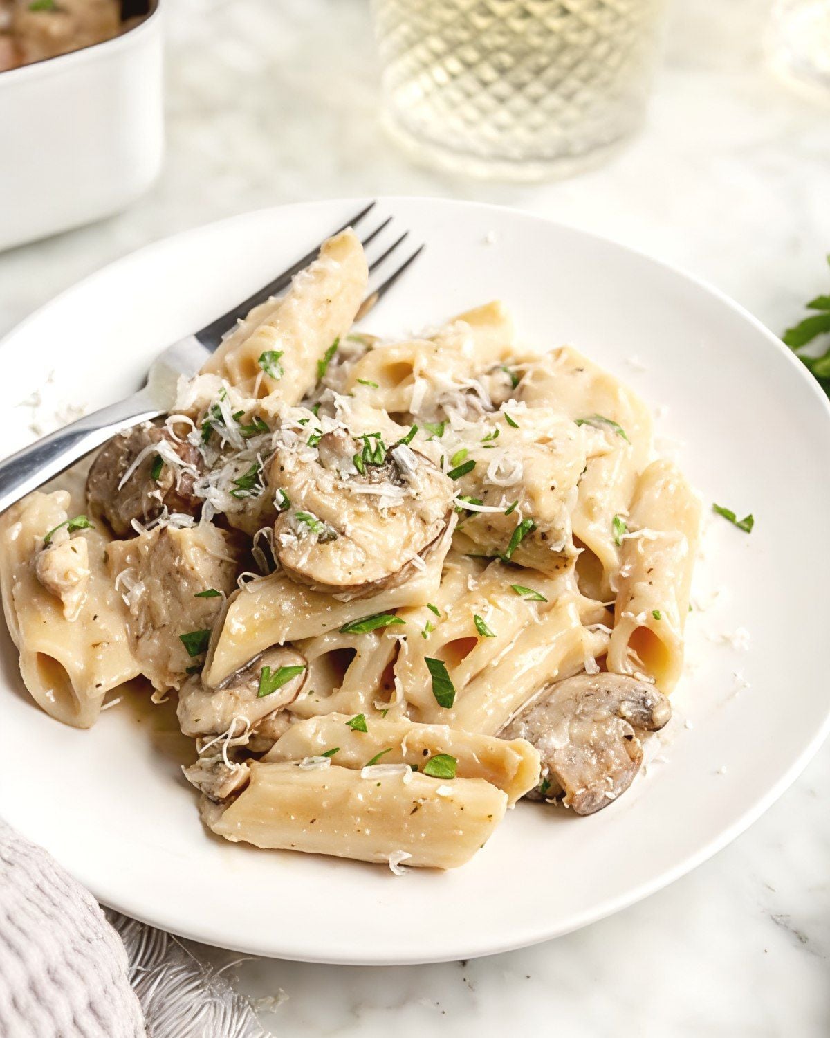 Alfredo pasta dump and bake casserole with mushrooms and parmesan cheese served on a white plate