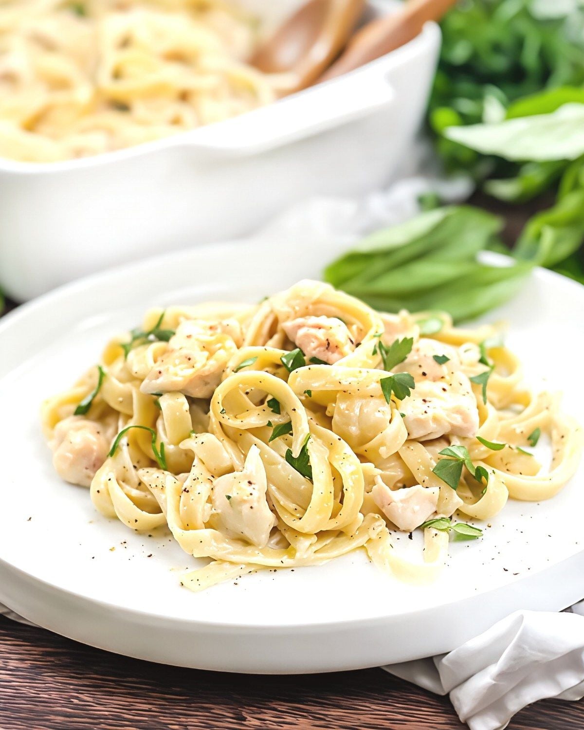 Chicken pasta bake with creamy alfredo sauce and fettuccine noodles served on a white plate