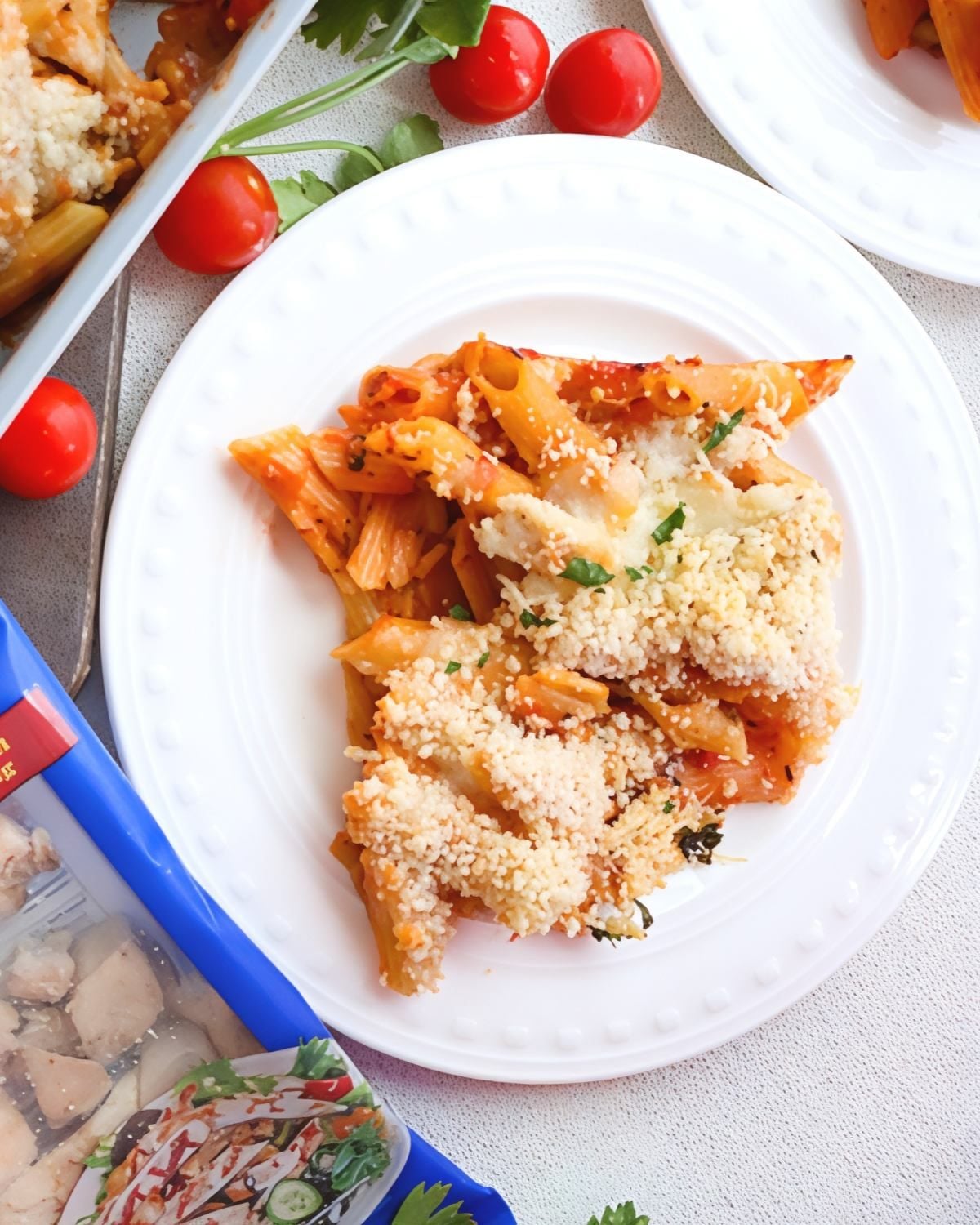 Chicken parmesan dump and bake pasta served on a white plate with fresh cherry tomatoes