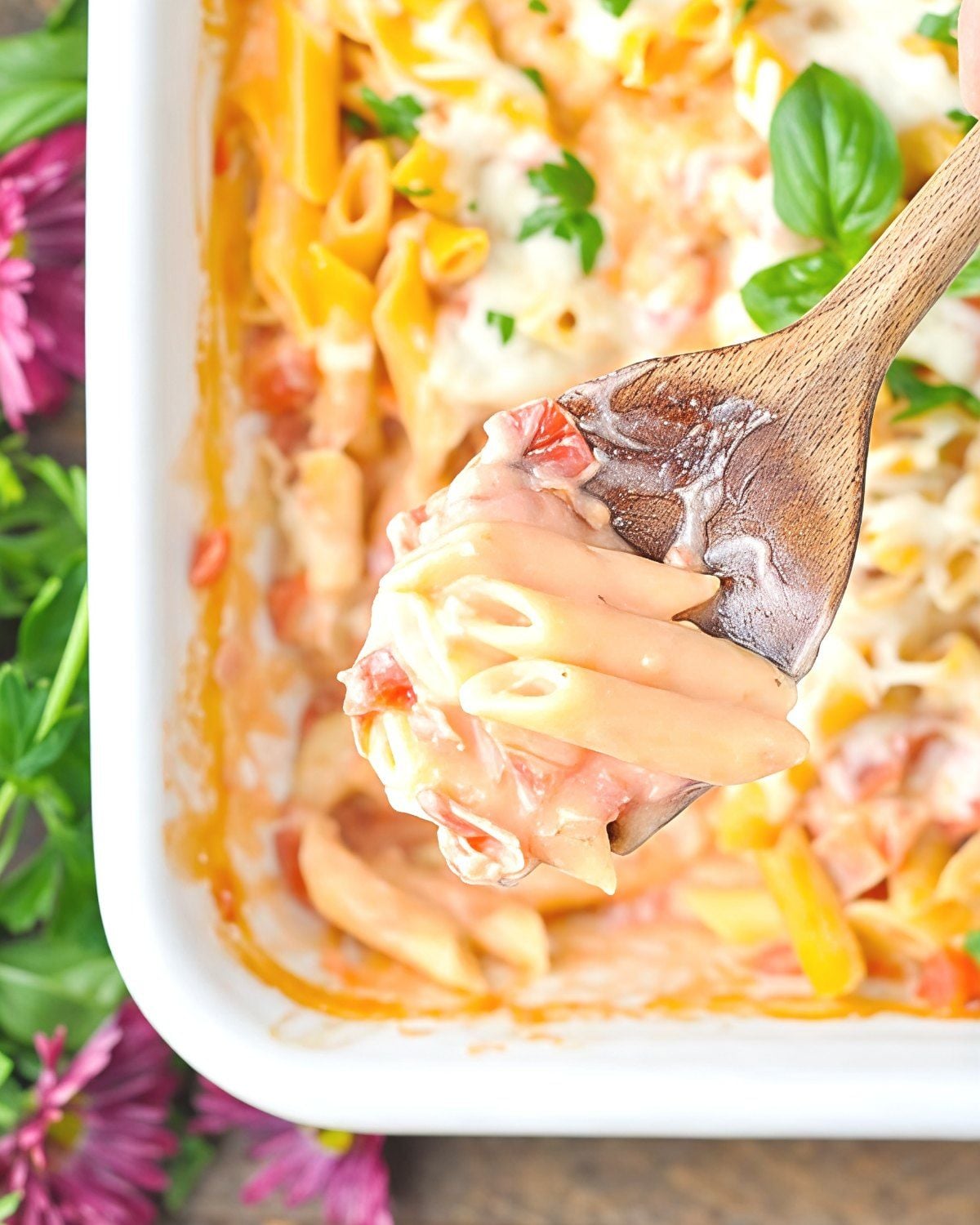 Dump and bake penne alla vodka pasta casserole in a white baking dish with a wooden spoon