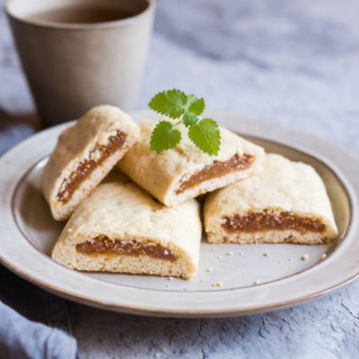 Fig Newtons in a white plate with fresh herbs as a garnish on the counter