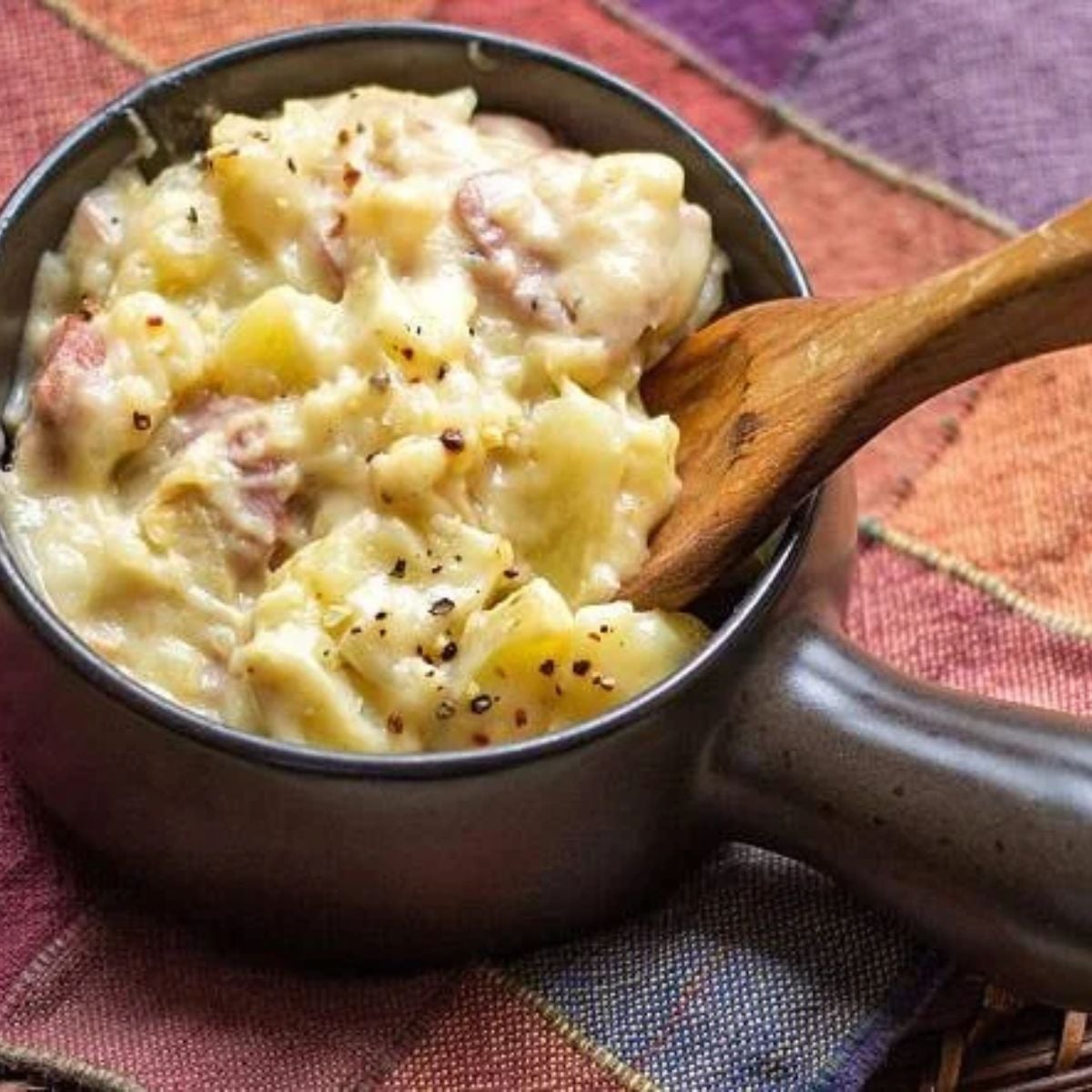 Ham and Scalloped Potatoes in a serving dish with a wooden spoon on the side