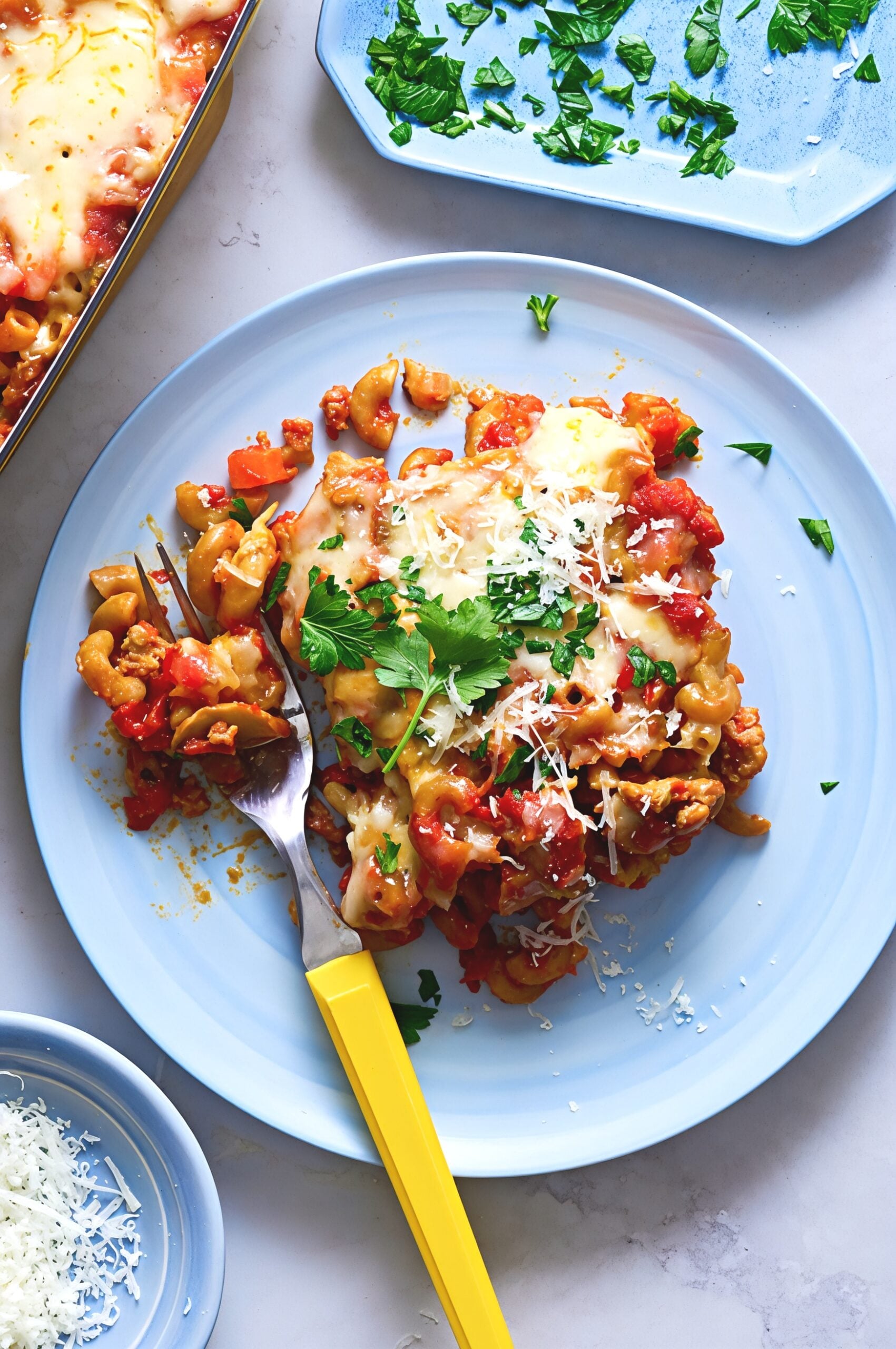 Macaroni casserole dump and bake pasta served on a blue plate with melted cheese and fresh herbs