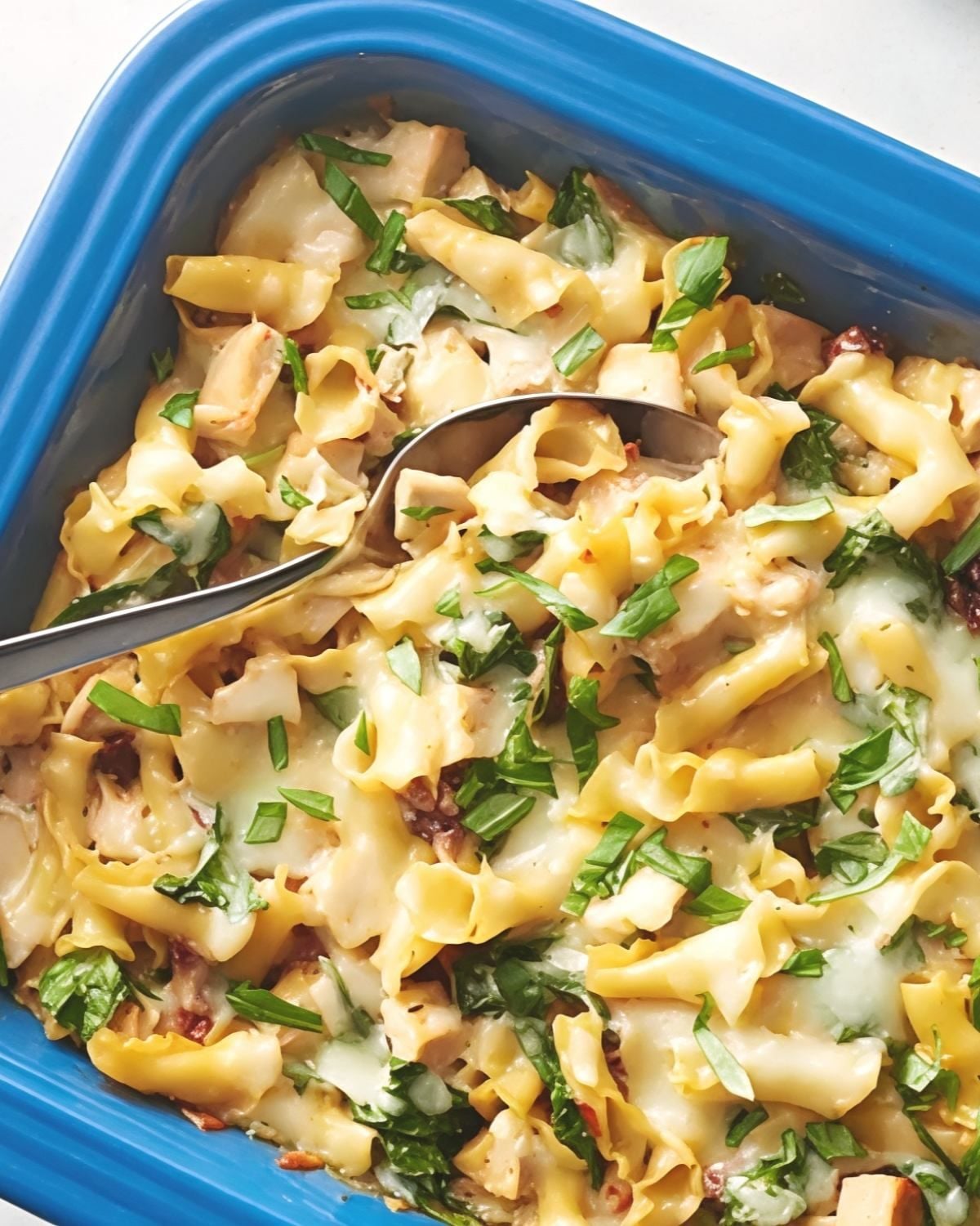 One pan Tuscan chicken pasta dump and bake casserole in a blue baking dish topped with fresh basil