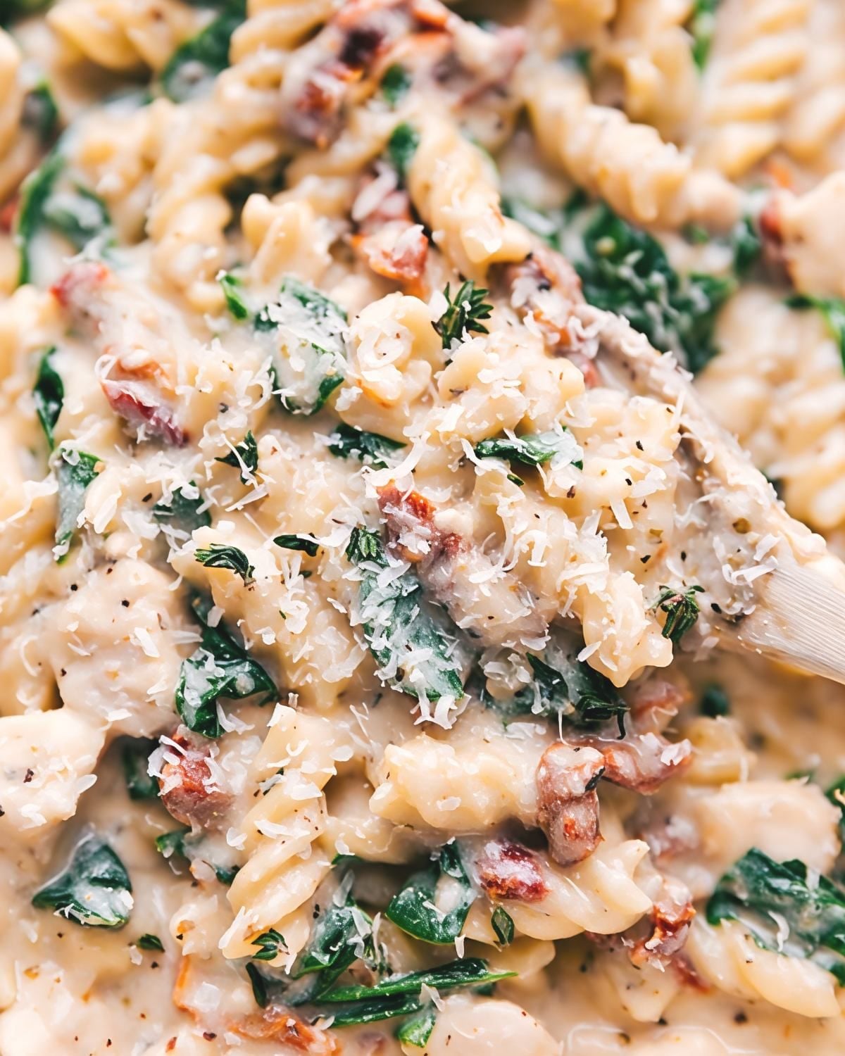 Creamy Tuscan chicken pasta with fusilli, spinach, sun-dried tomatoes, and parmesan cheese