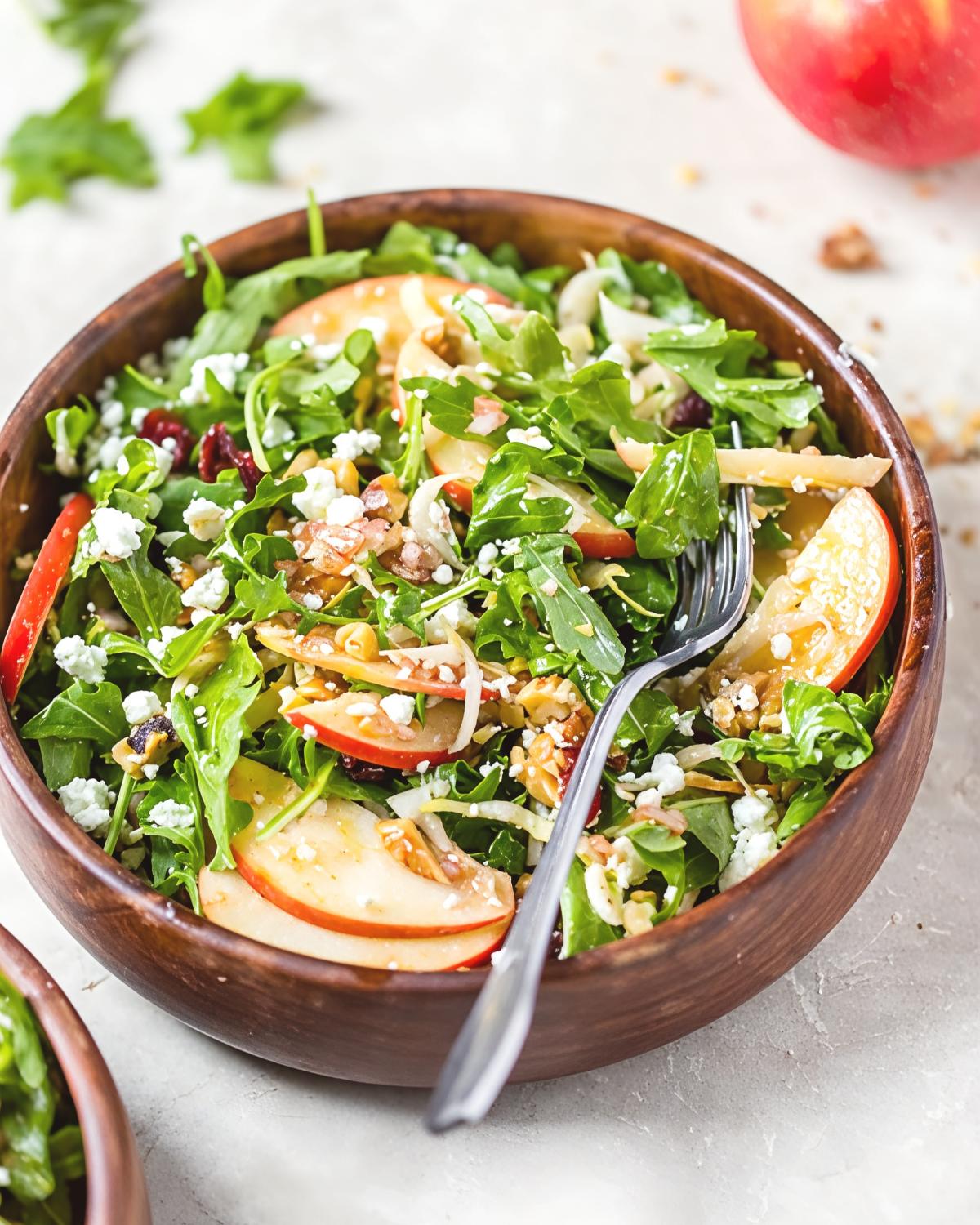 Fresh apple walnut salad with arugula, sliced red apples, crumbled feta cheese, and dried cranberries served in a wooden bowl, perfect as quick and easy last minute potluck ideas.