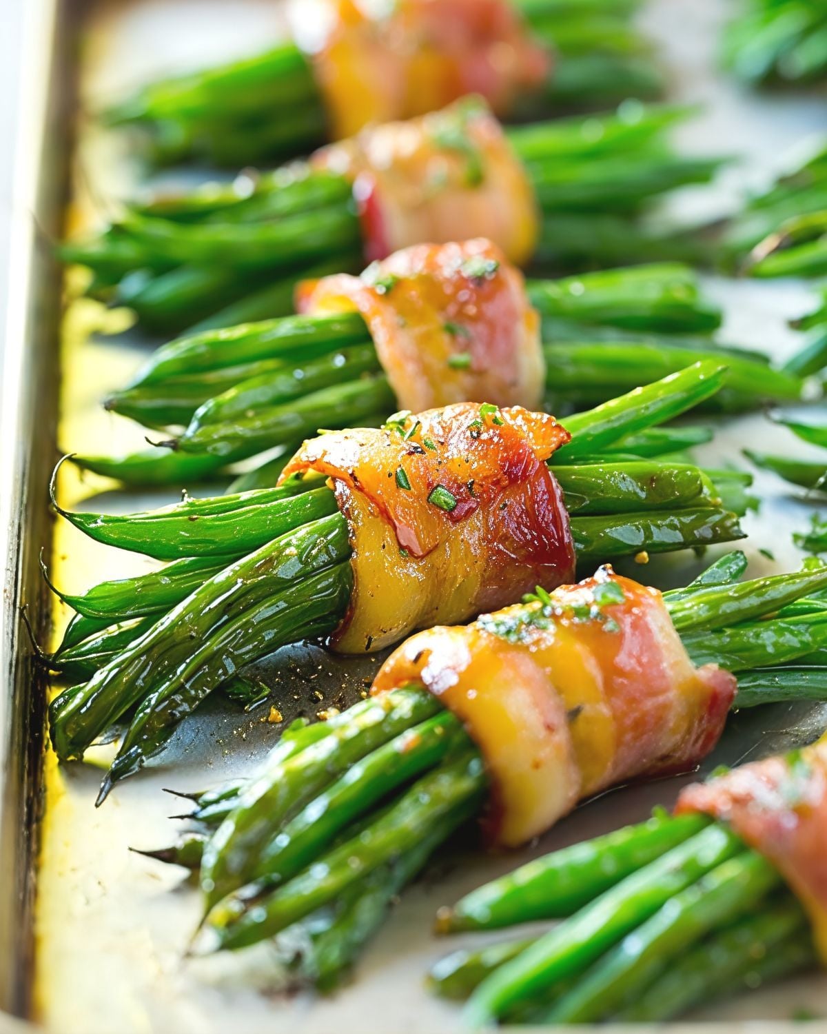 Fresh green bean bundles wrapped tightly in glazed crispy bacon on a baking sheet, served as one of the best gluten-free Thanksgiving side dishes.