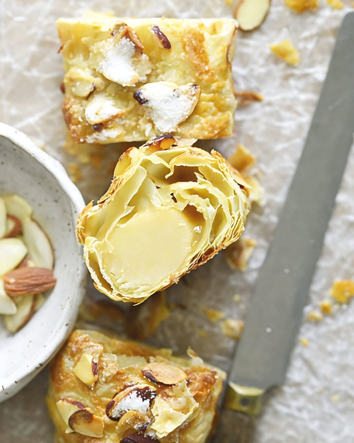 A sliced Dutch Banketstaaf showing flaky puff pastry filled with almond paste and topped with sliced almonds, featured as a traditional European Christmas dessert.