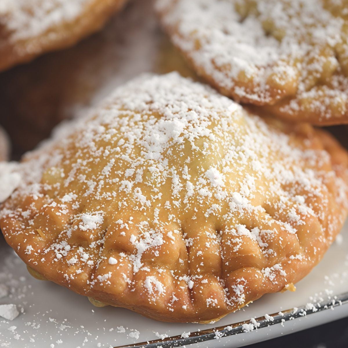 A close-up shot of freshly fried Bourekia me Anari pastries dusted with powdered sugar, featured as one of the best Christmas desserts of Europe.