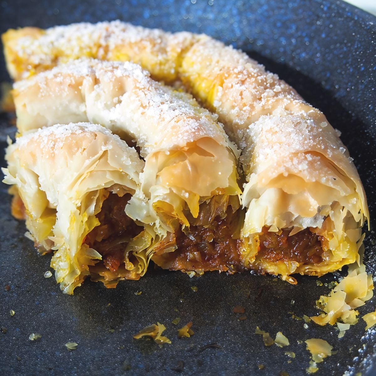 Crispy layers of rolled Bulgarian Tikvenik pumpkin strudel filled with spiced grated pumpkin and walnuts dusted with powdered sugar, served as a classic European Christmas dessert.