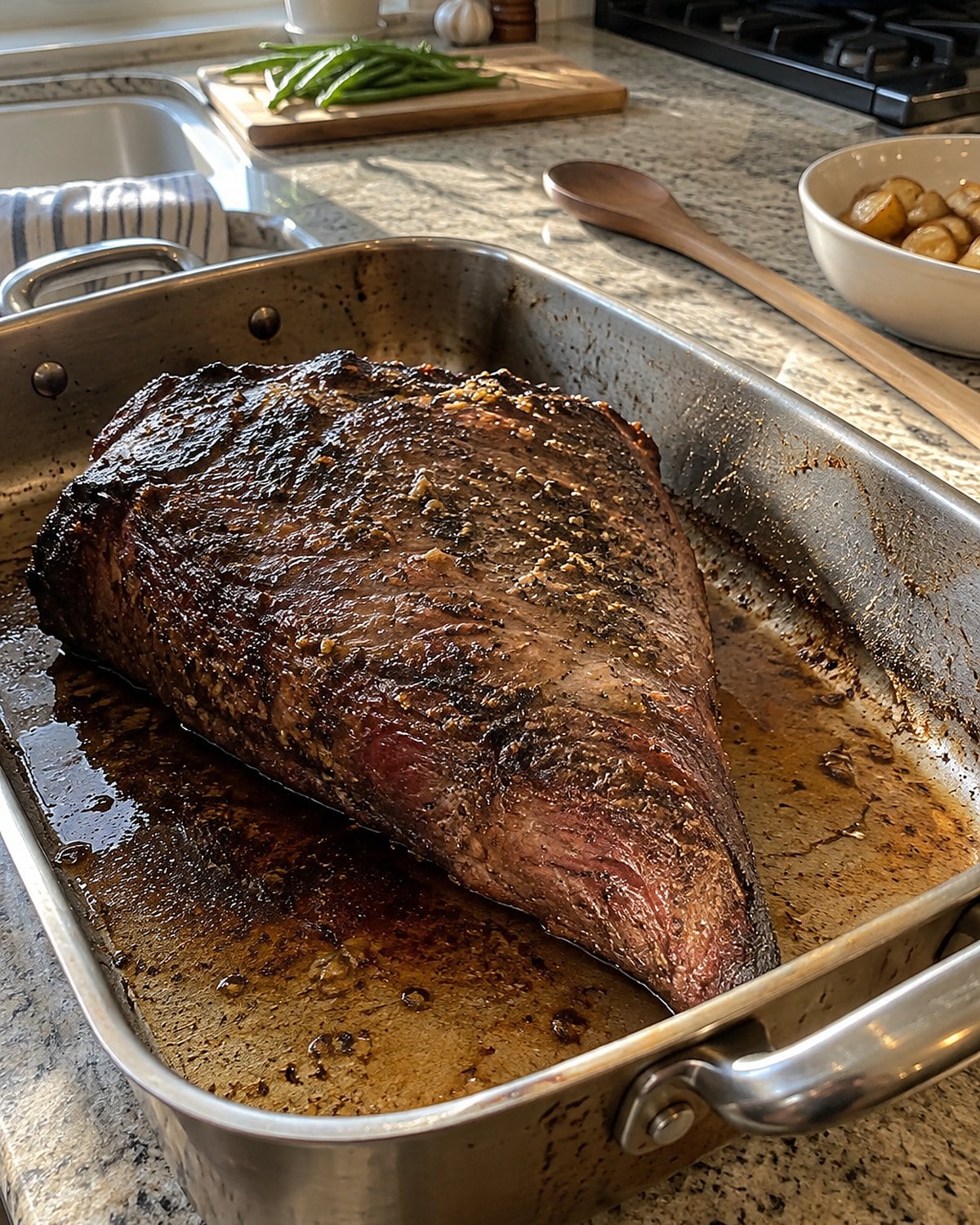 A triangular tri-tip roast in a Sunday roasting pan, its narrow point visible.