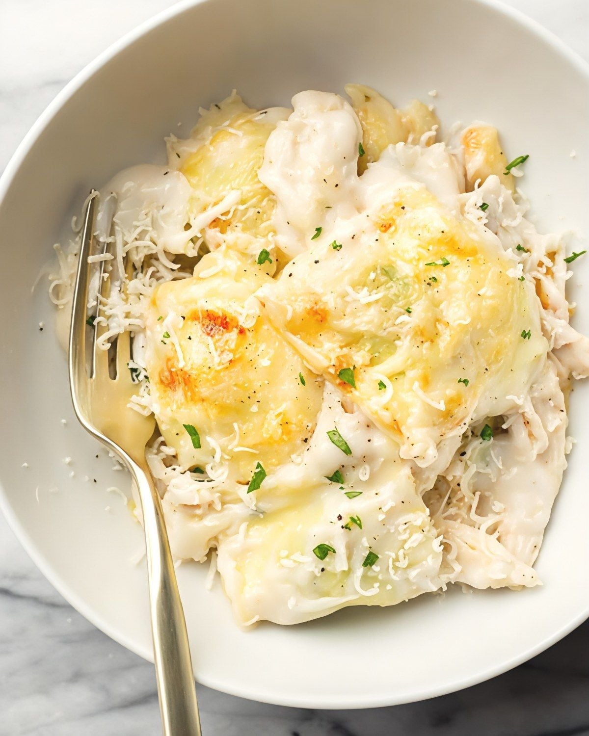 Chicken alfredo ravioli dump and bake pasta served in a white bowl with a fork
