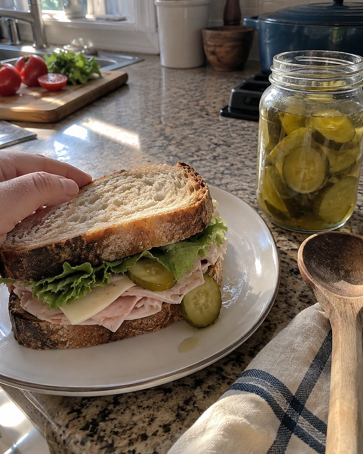 An open jar of dill pickles beside a thick sandwich on the counter.