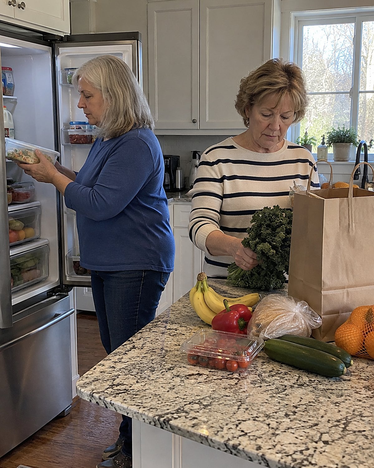 Two pairs of hands unpacking grocery bags on a kitchen counter, with cold food headed toward an open fridge.