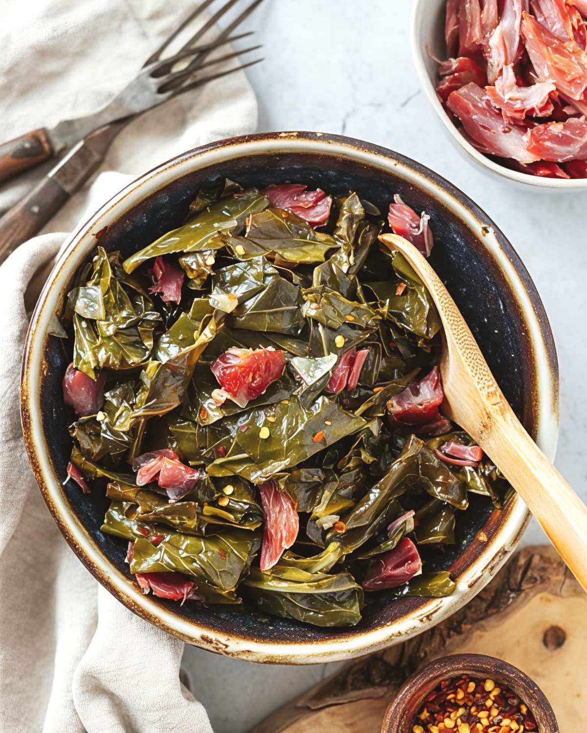 A bowl of tender slow-cooked collard greens tossed with shredded meat and red pepper flakes, featured as one of the best crockpot thanksgiving sides.