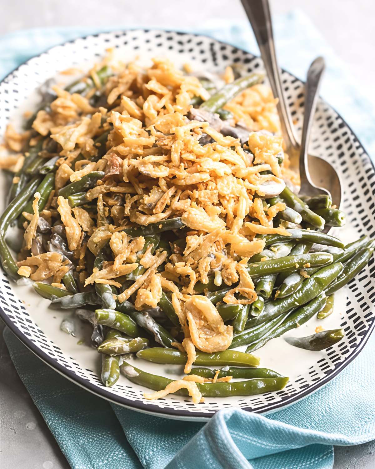 A patterned serving platter filled with tender slow cooker green bean casserole generously topped with crispy fried onions, featured among delicious crockpot thanksgiving sides.