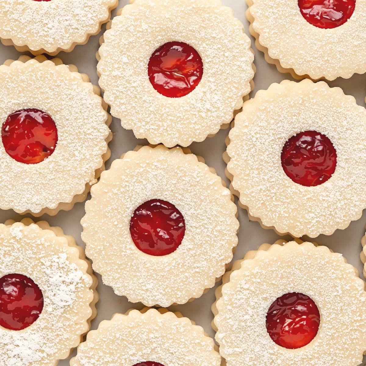 Traditional Czech Vánoční Cukrovi Linzer sandwich cookies dusted with powdered sugar and filled with bright red jam, featured as a classic European Christmas dessert.