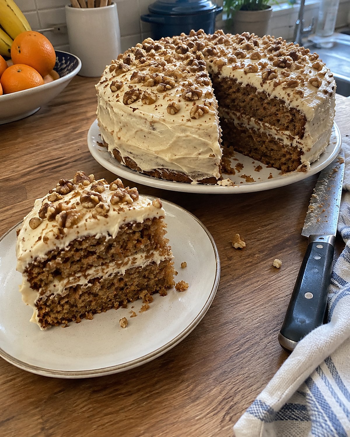 A thin slice of homemade cake rests on a small plate beside the partly cut cake.
