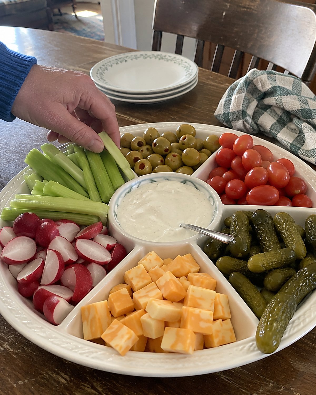 A slightly uneven relish tray with celery, olives and pickles on a church hall table.