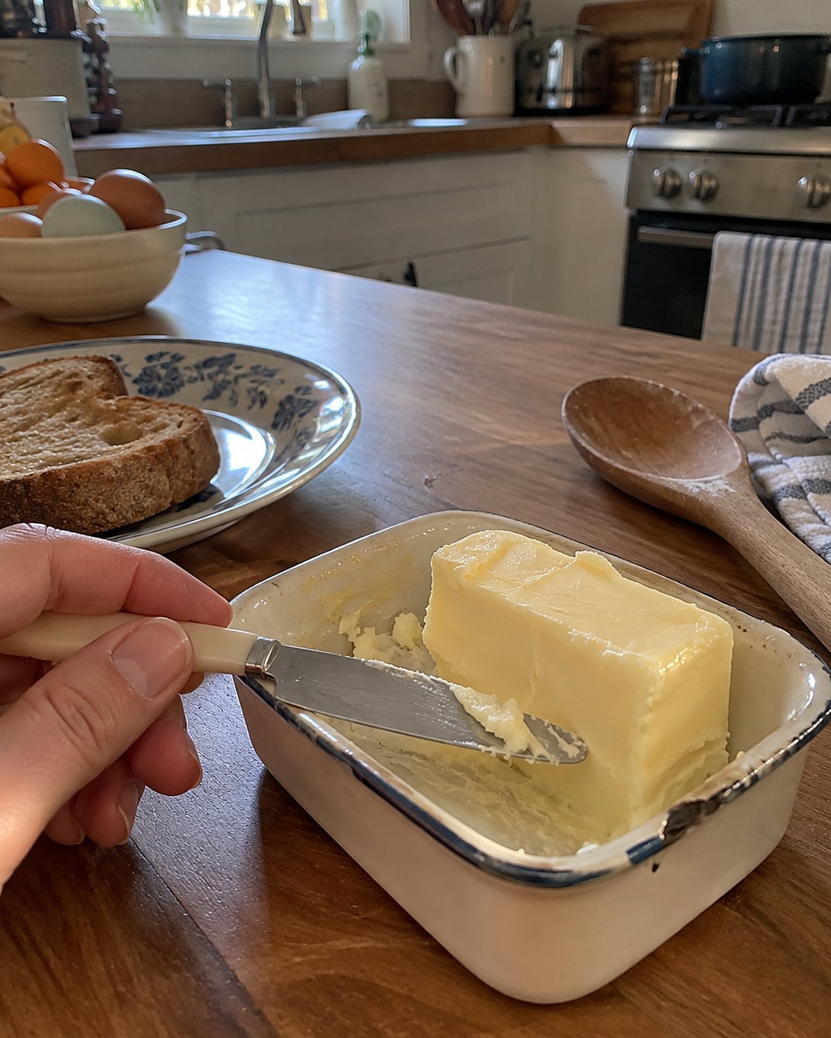 A butter dish with a small spreader resting across its rim on a kitchen counter.