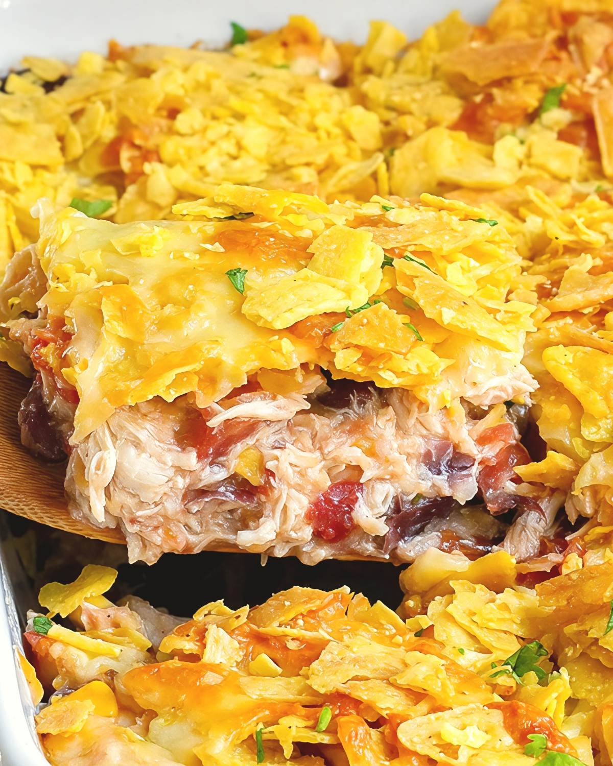 Cheesy Doritos chicken casserole being served from a baking dish, a quick dump and bake recipe for dinner