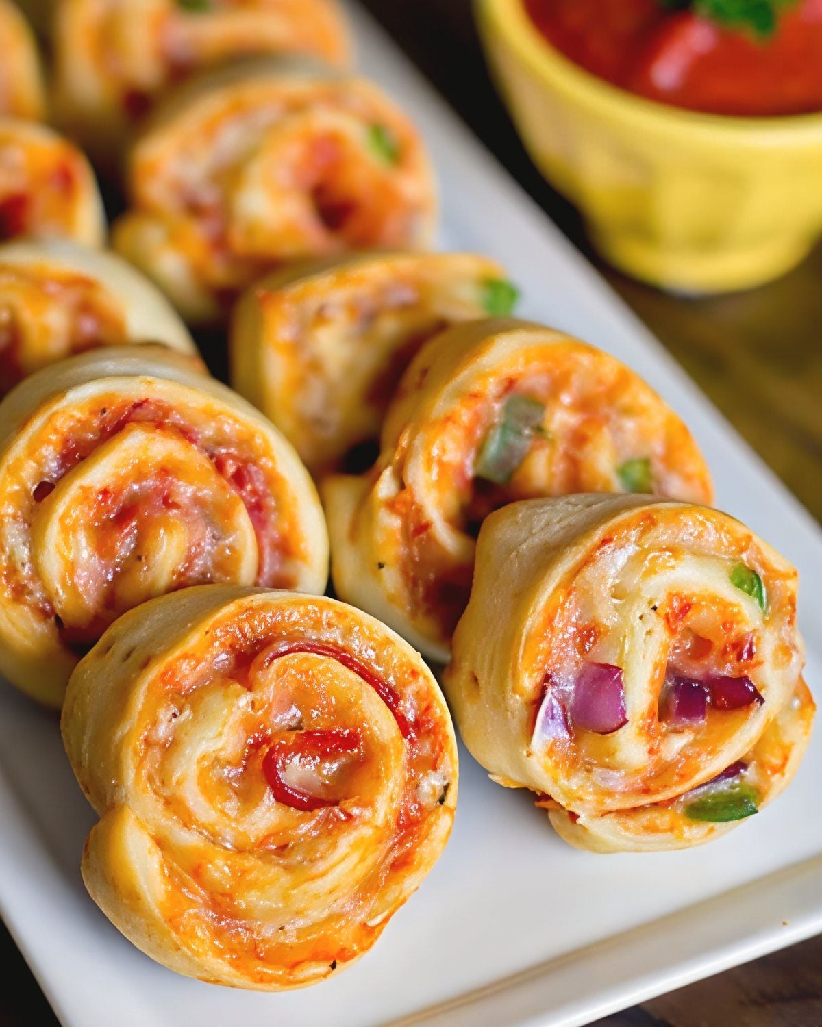 Golden-baked easy pizza pinwheels filled with melted cheese, savory pepperoni, and marinara sauce rolled in crisp pastry dough, serving as delicious last minute potluck ideas.