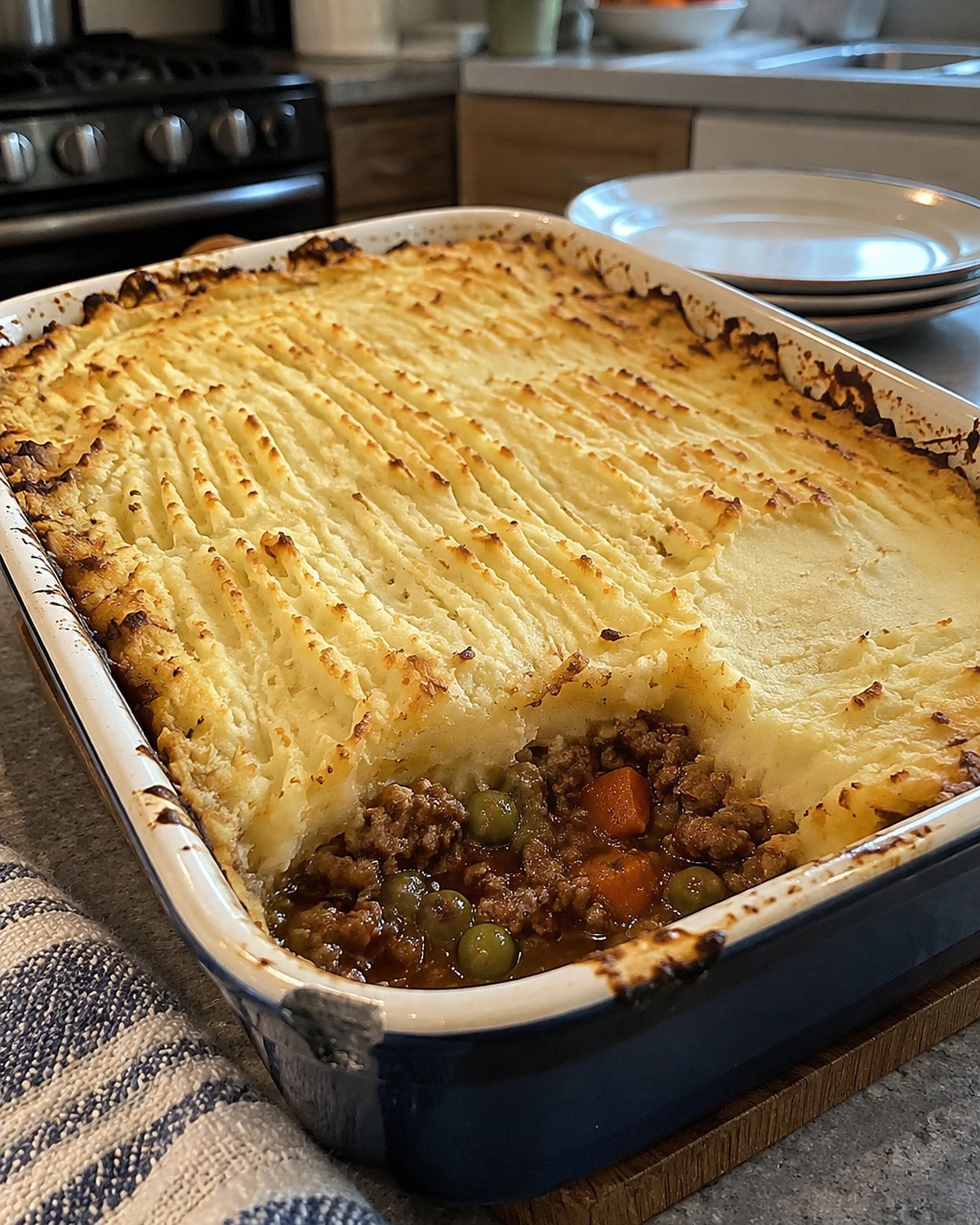 Fork ridges pressed into mashed potatoes atop a shepherdโs pie in a baking dish.