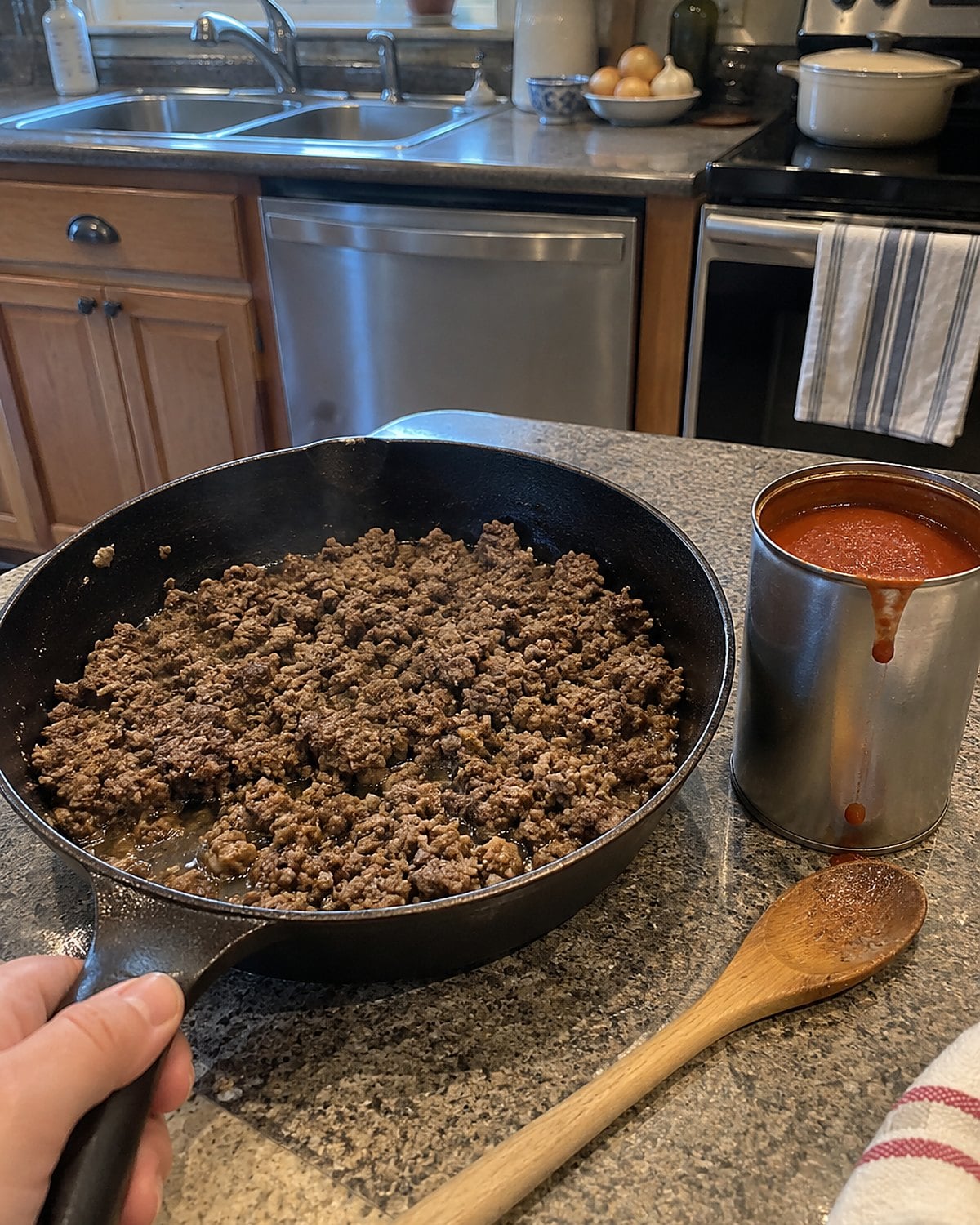 A can of condensed tomato soup beside a skillet of browned beef on the counter.