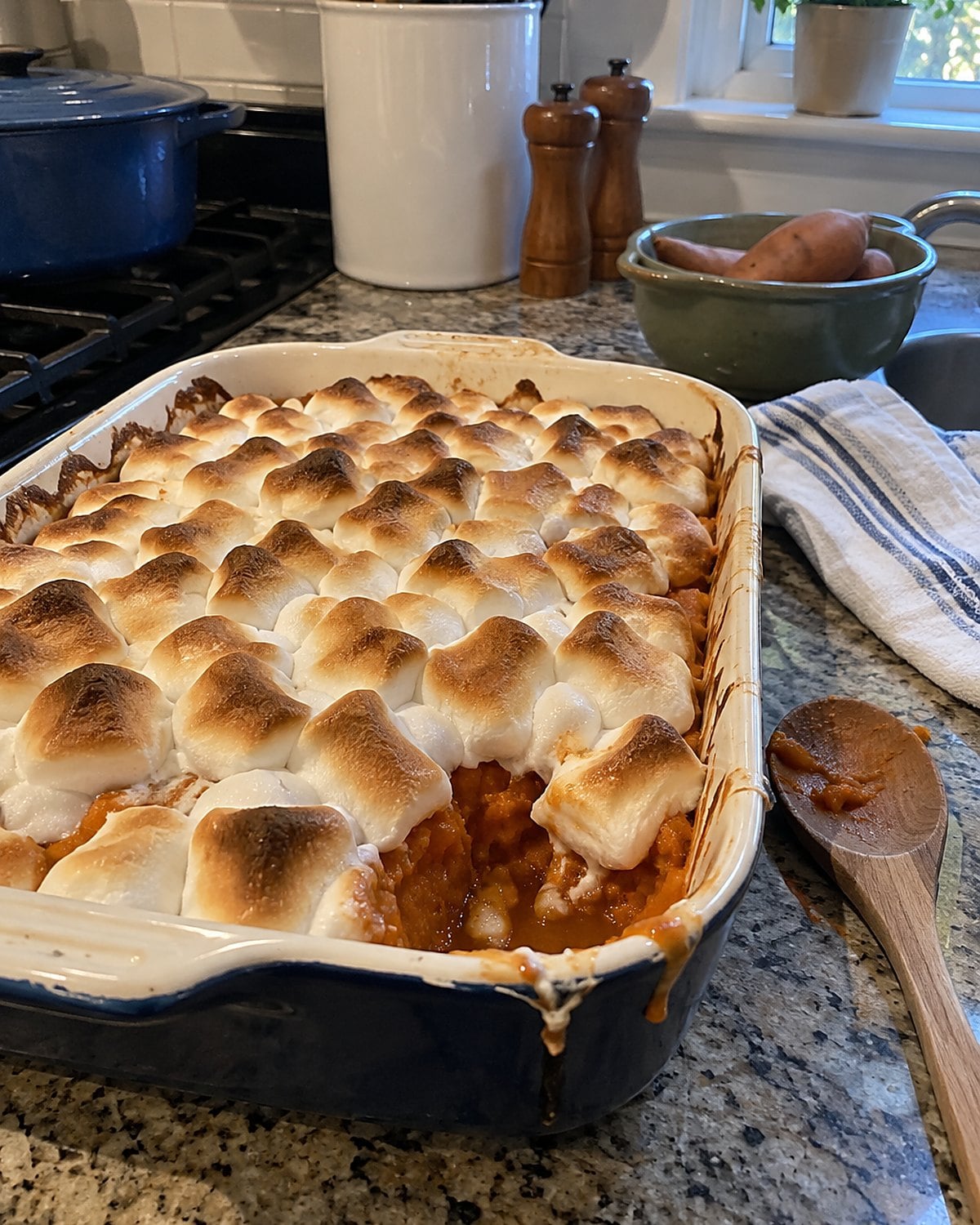 Marshmallows browning unevenly on sweet potatoes in a small baking dish.