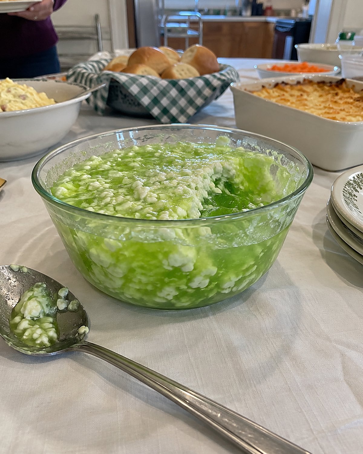 Lime gelatin with visible cottage cheese curds in a small bowl on a church hall serving table.