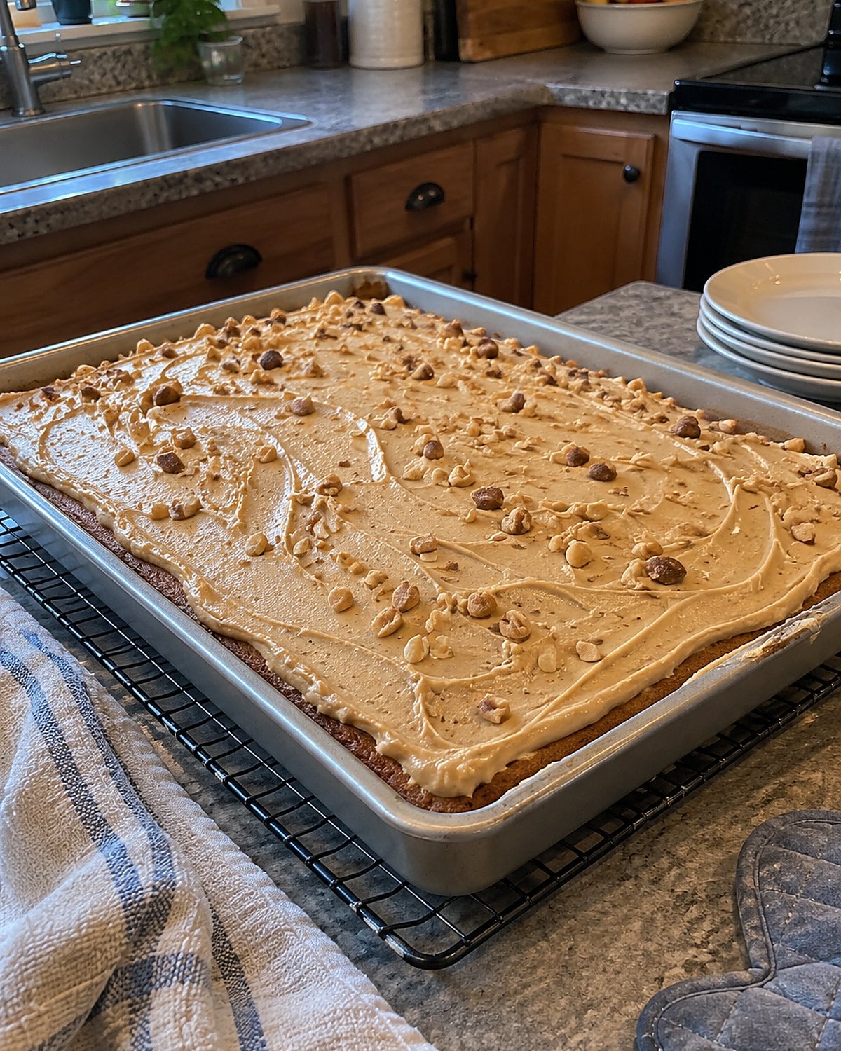 A peanut butter sheet cake cooling in its pan on a wire rack, with one crooked icing line.