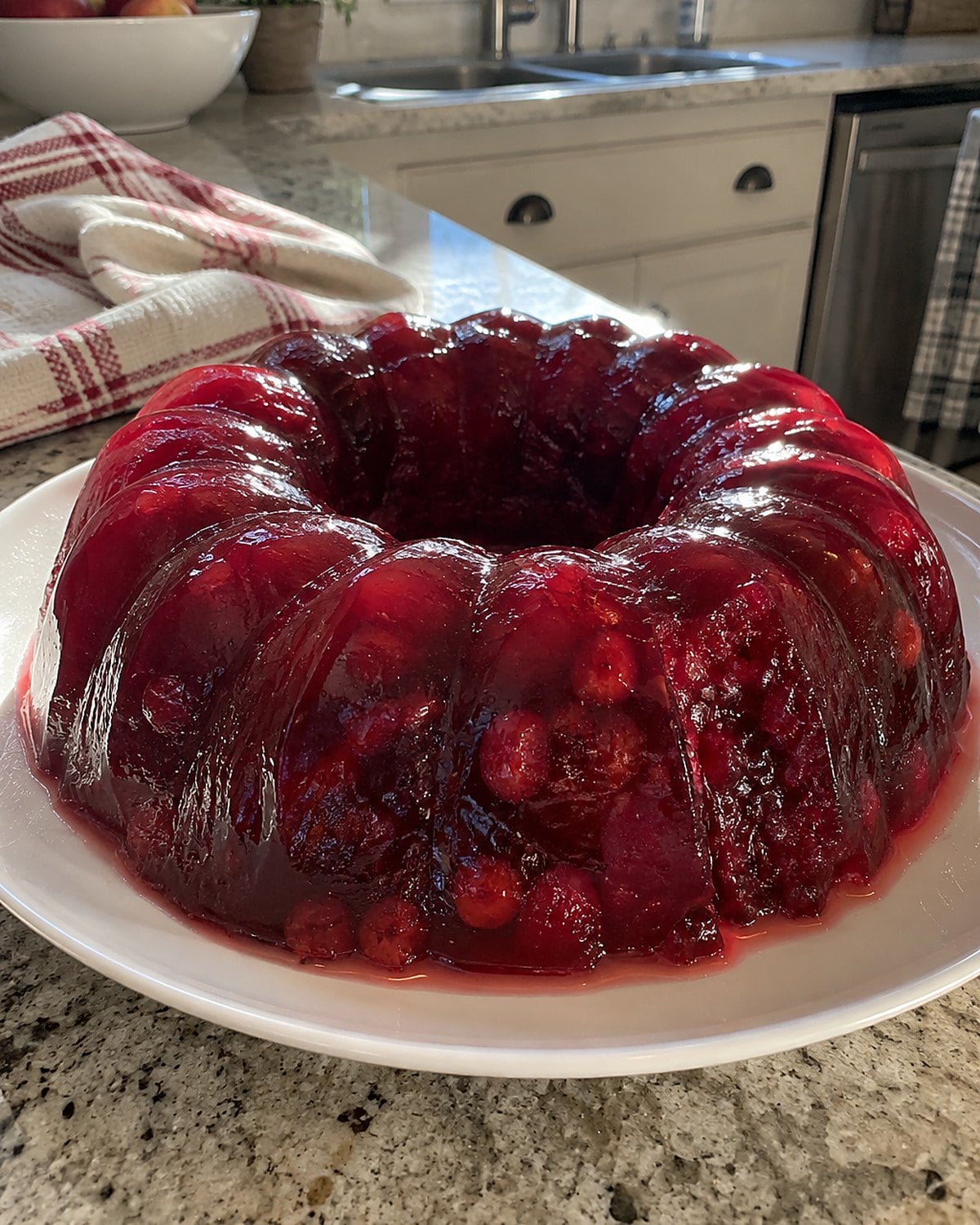 A fluted cranberry salad on a plain plate, with a little juice pooling near the edge.