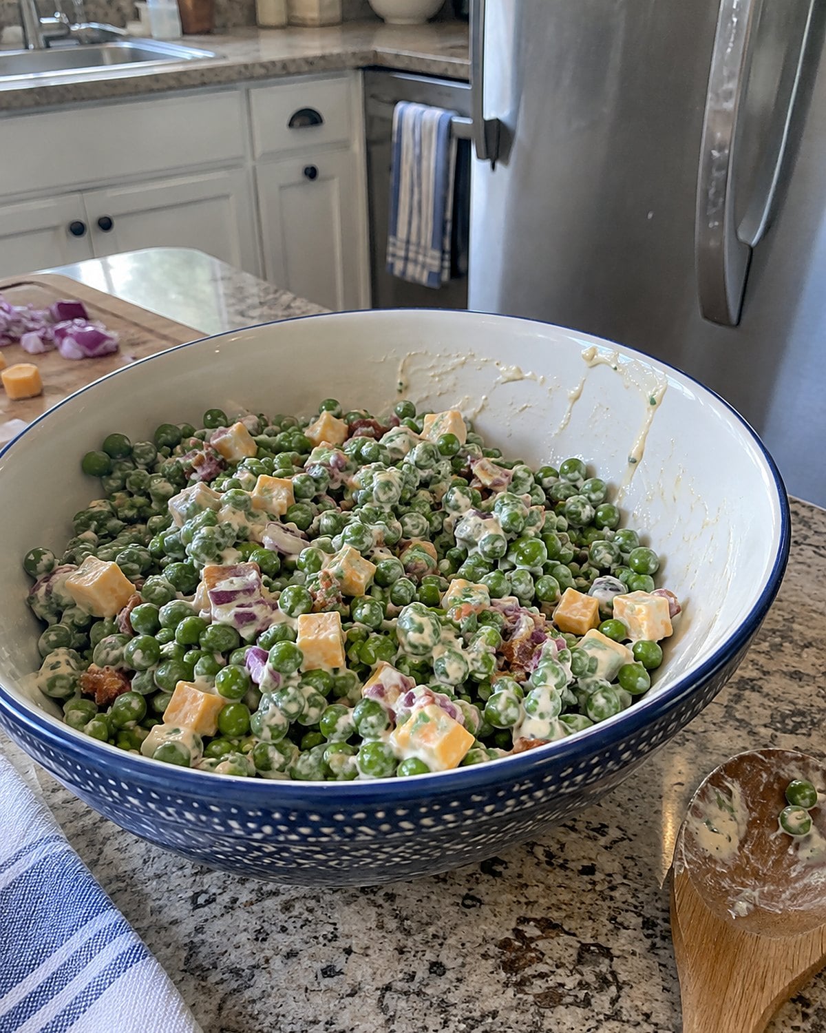 A bowl of pea salad with small cheddar cubes sits near the refrigerator door.