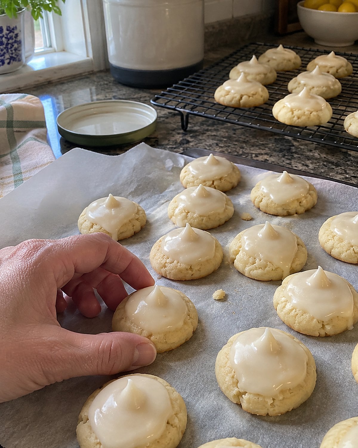 Pale anise drops with raised caps sit on parchment near a cooling rack.