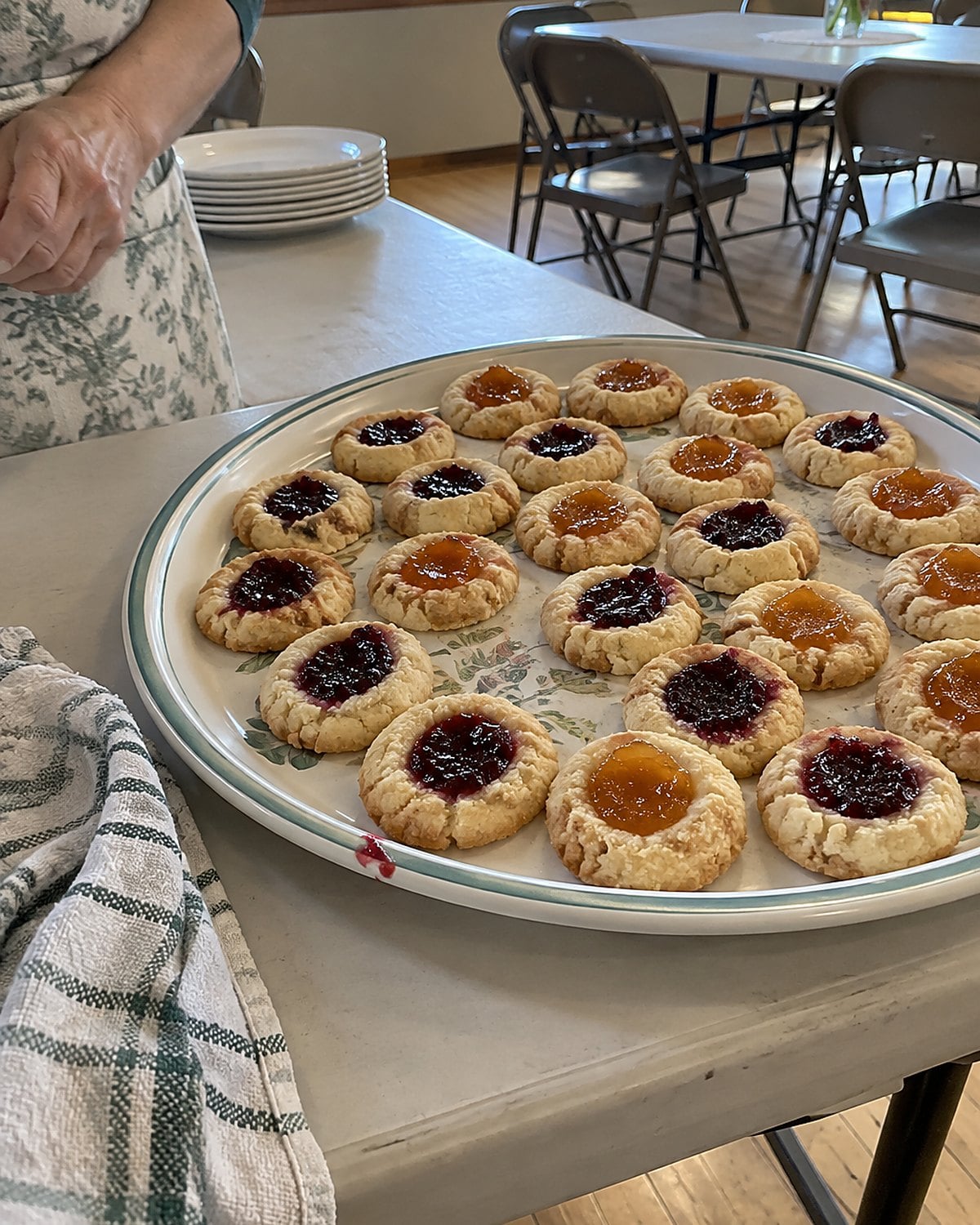Raspberry and apricot thumbprints sit in a single layer on a church hall serving tray.
