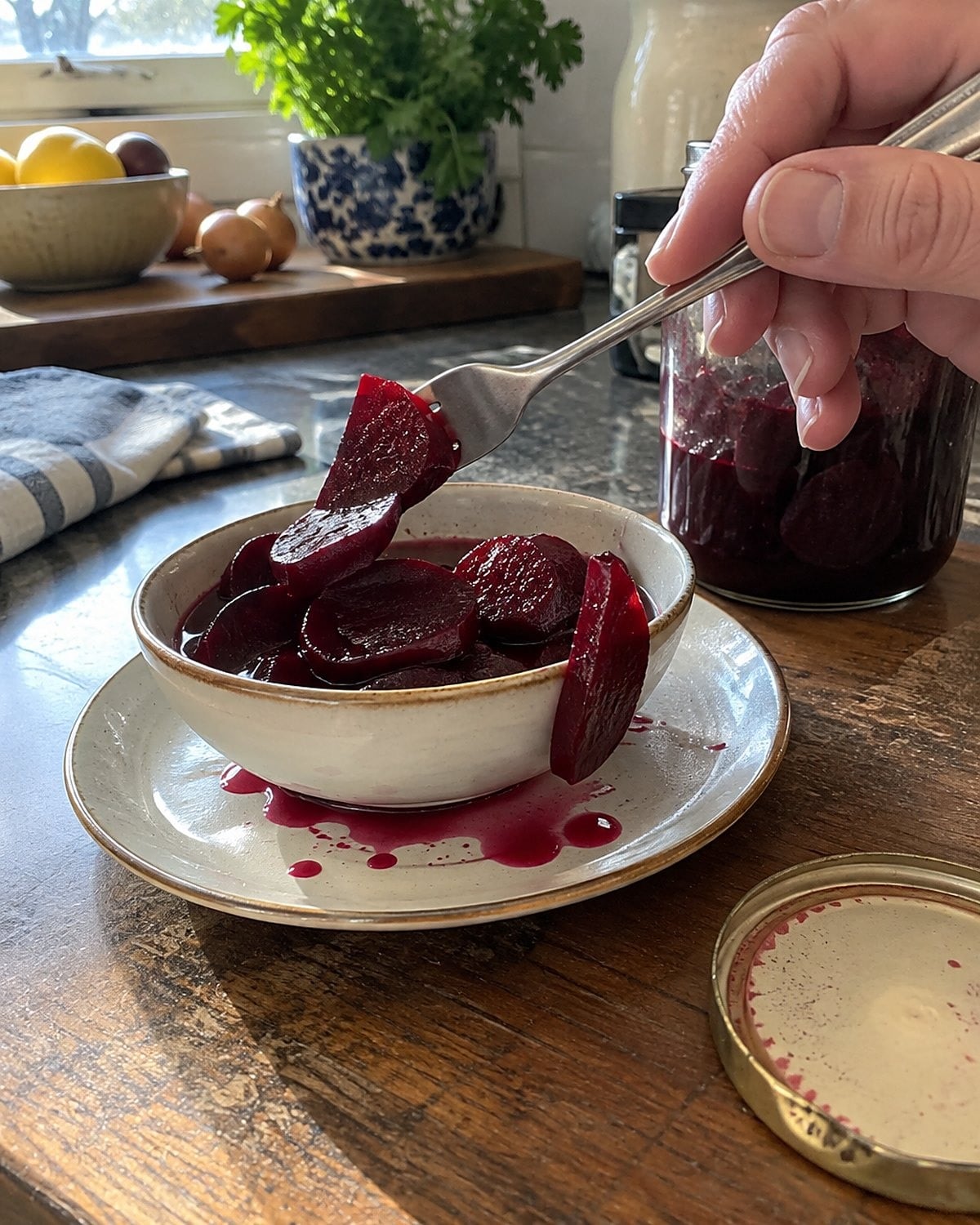 A small bowl of pickled beets with pink drops on the saucer underneath.